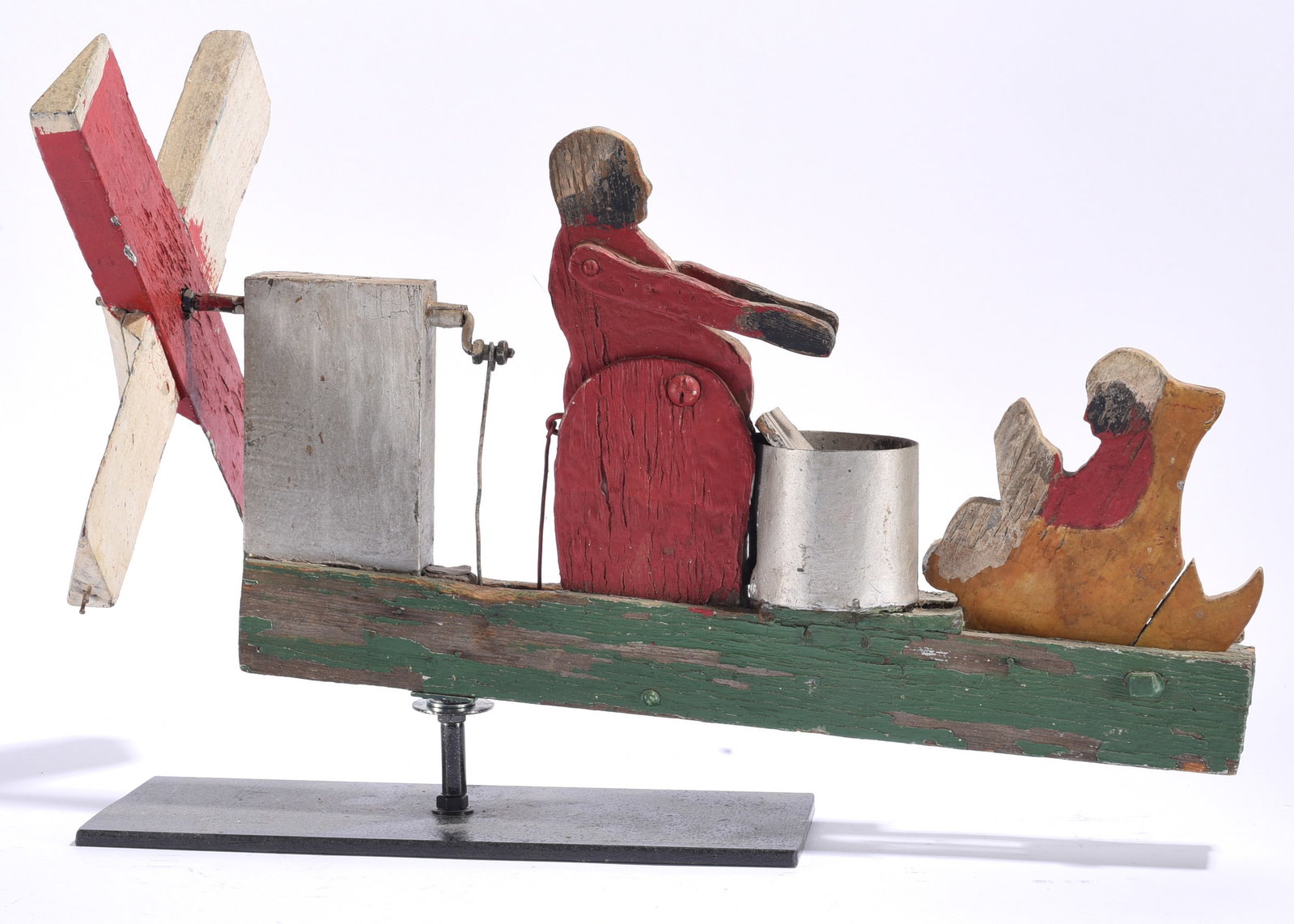 Antique Painted Folk Art Whirligig with Base: 17"x11" Antique painted folk art whirligig depicting two figures aboard a small green boat, one operating a large red-and-white propeller and another seated figure holding an object. Constructed from 