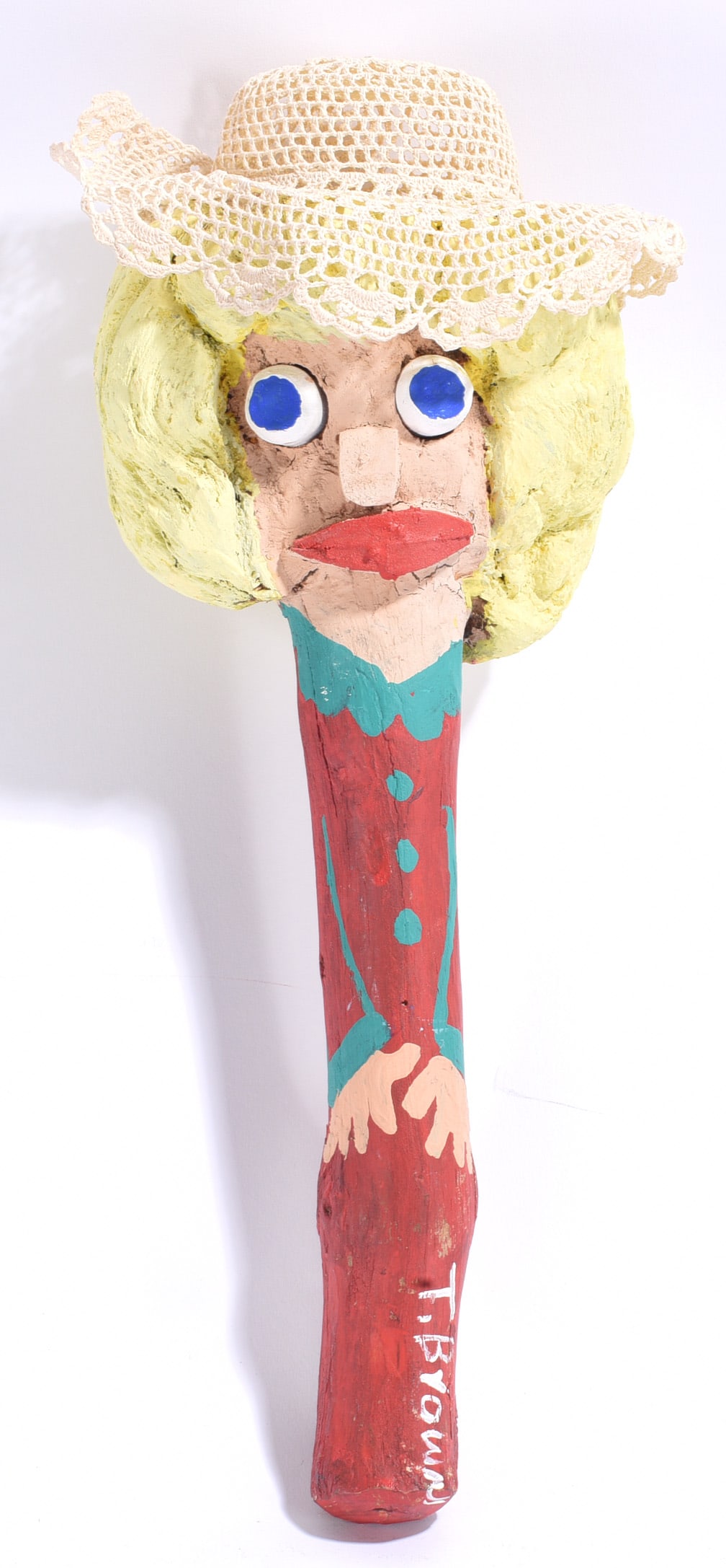 Tubby Brown Folk Art Carved and Painted Root Stick: 16" Tubby Brown folk art carved and painted root stick depicting a woman with large applied eyes, blonde hair, red dress and a crocheted white hat. Signed "T. Brown" near the lower portion, the work m