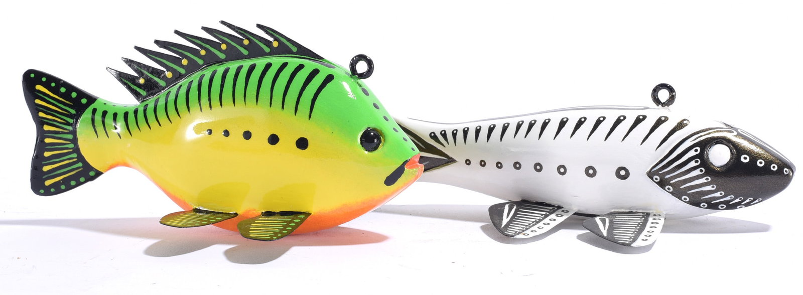 Wooden Fish Decoys signed TB: Largest is 6"x3" Two wooden fish decoys signed TB, each individually carved and brightly painted. One features vivid green and yellow coloration with a dramatic spined dorsal fin, while the companion 