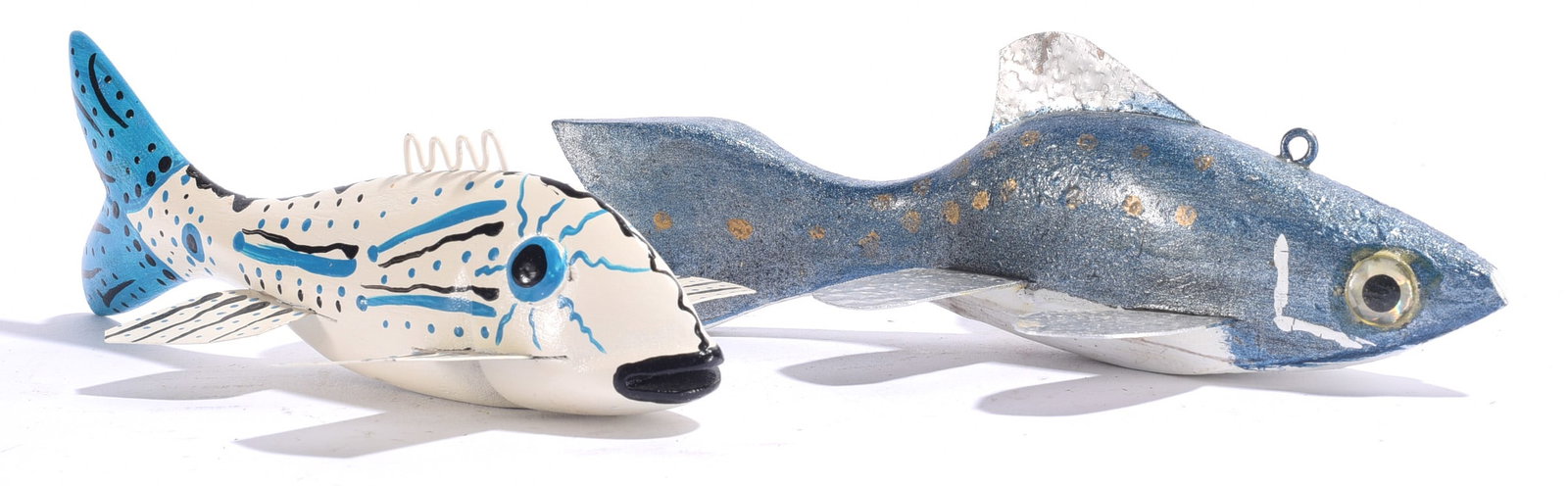Ken Foster Folk Art Fish Decoys: Both about 7"x2" Pair of carved and painted folk art fish decoys, one white with blue and black linear decoration and the other metallic blue with gold spotting. Both feature applied fins, inset eyes 