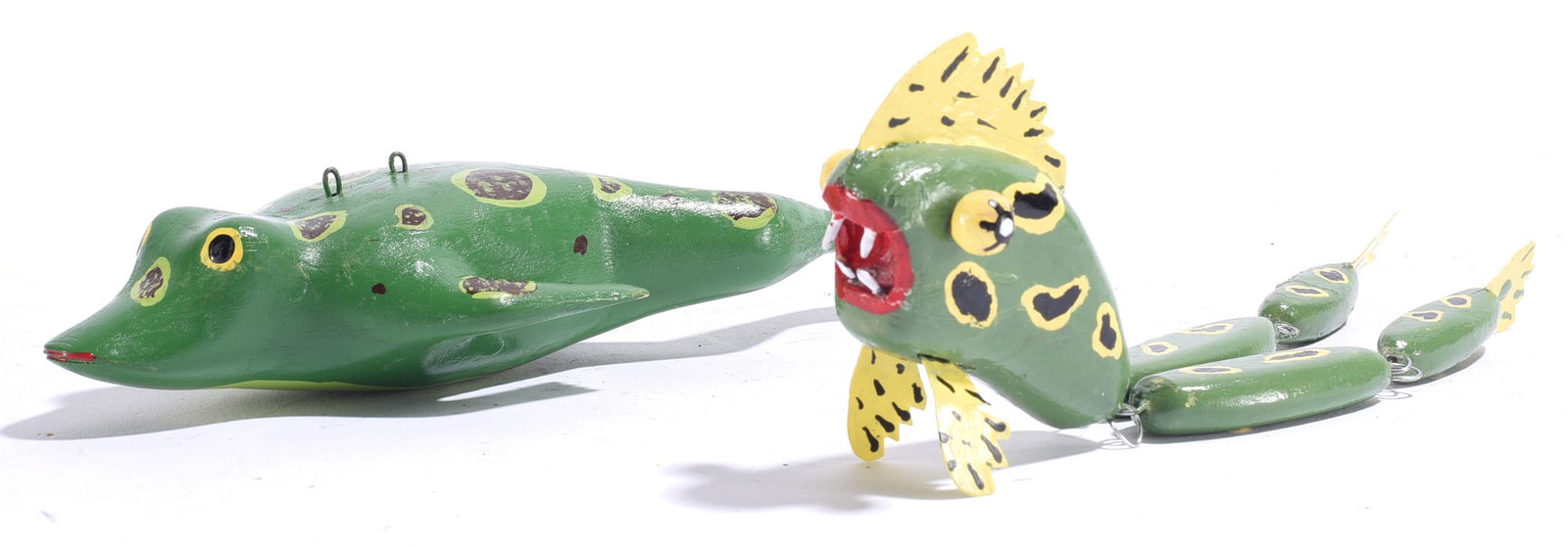 Vintage Carved Fish Decoys (2): Both approximately 7"x1.5" Pair of carved and painted wooden fish decoys, including a conventional green fish and an articulated fish constructed in multiple linked sections with yellow fins and