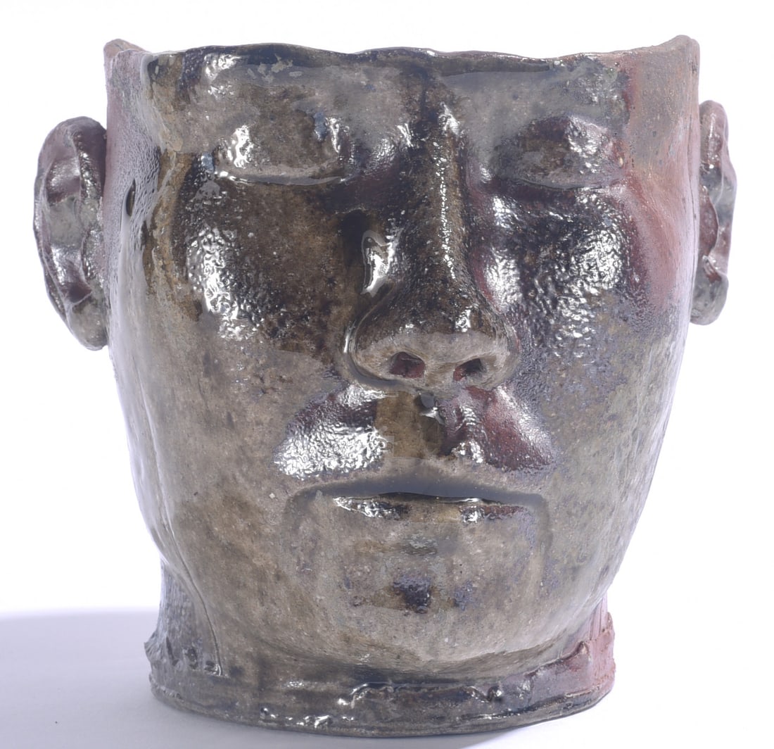 Contemporary Pottery Face Vase: 6" Contemporary folk pottery face vase with expressive sculpted human features, applied ears and irregular rim. Finished in a dark variegated glaze with brown, gray and reddish tones.
