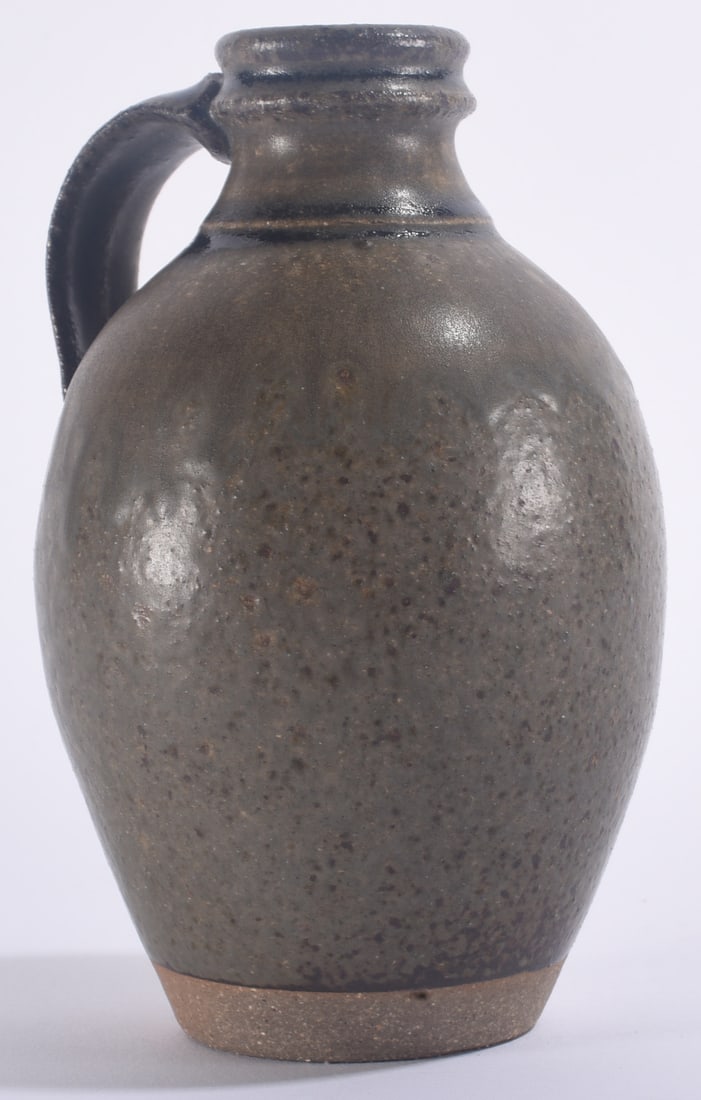 Contemporary Pottery Jug Alkaline Glaze: 6" Contemporary folk pottery face vase with expressive sculpted human features, applied ears and irregular rim. Finished in a dark variegated glaze with brown, gray and reddish tones. Stoneware potter