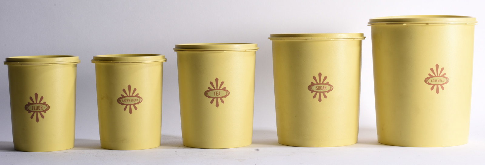1970s Tupperware Servalier Nesting Canister Set: Largest 9" Vintage circa 1970s Tupperware Servalier nesting canister set consisting of five graduated yellow containers labeled Flour, Brown Sugar, Tea, Sugar, and Cornmeal. Classic mid-century kitche