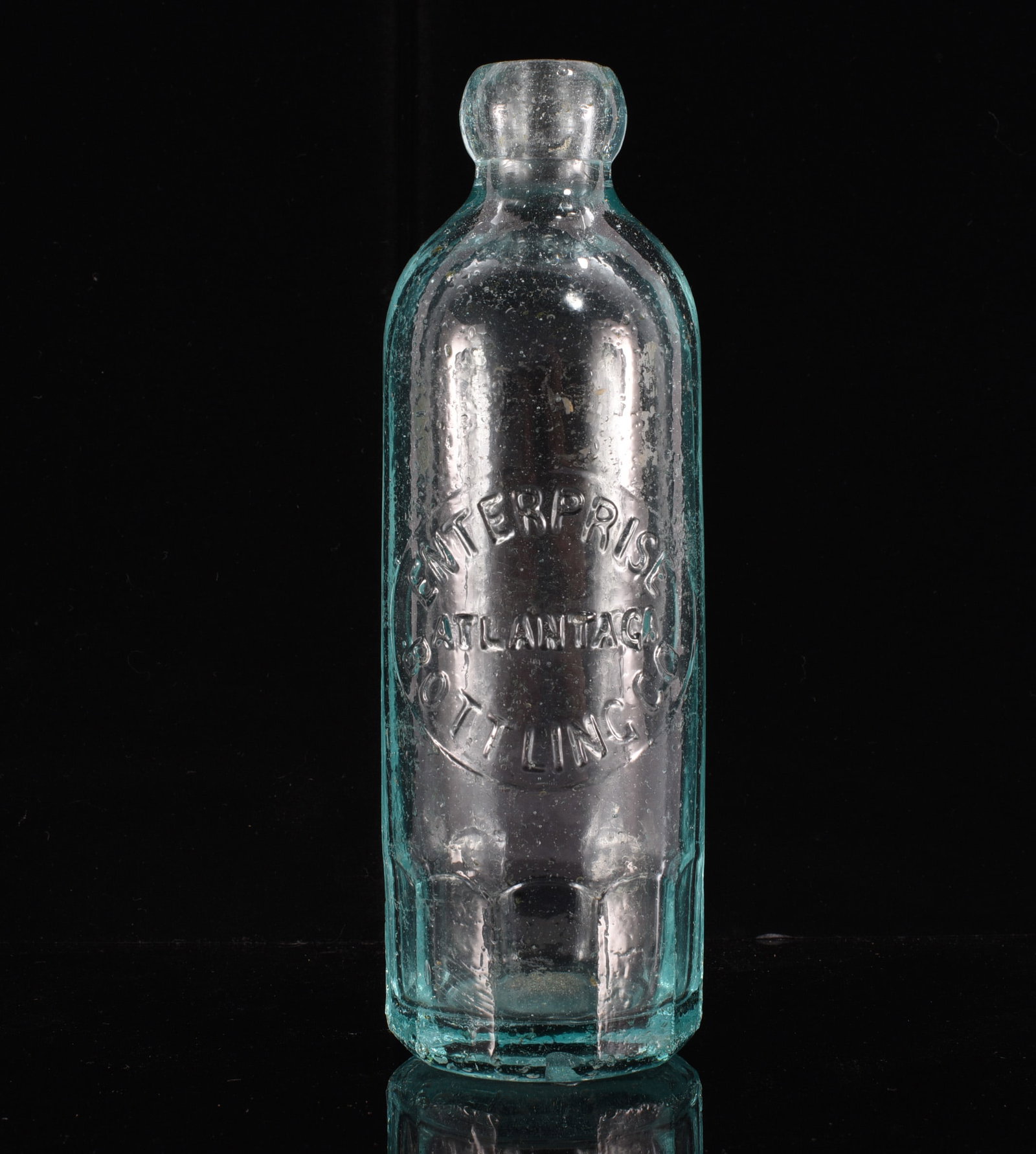 Enterprise Bottling Co. Atlanta GA Hutchinson Soda Bottle: 7" Antique aqua glass Hutchinson soda bottle embossed "Enterprise / Atlanta, Ga. / Bottling Co." within an oval panel. Heavy glass construction with blob top and attractive aqua coloration. An appeali