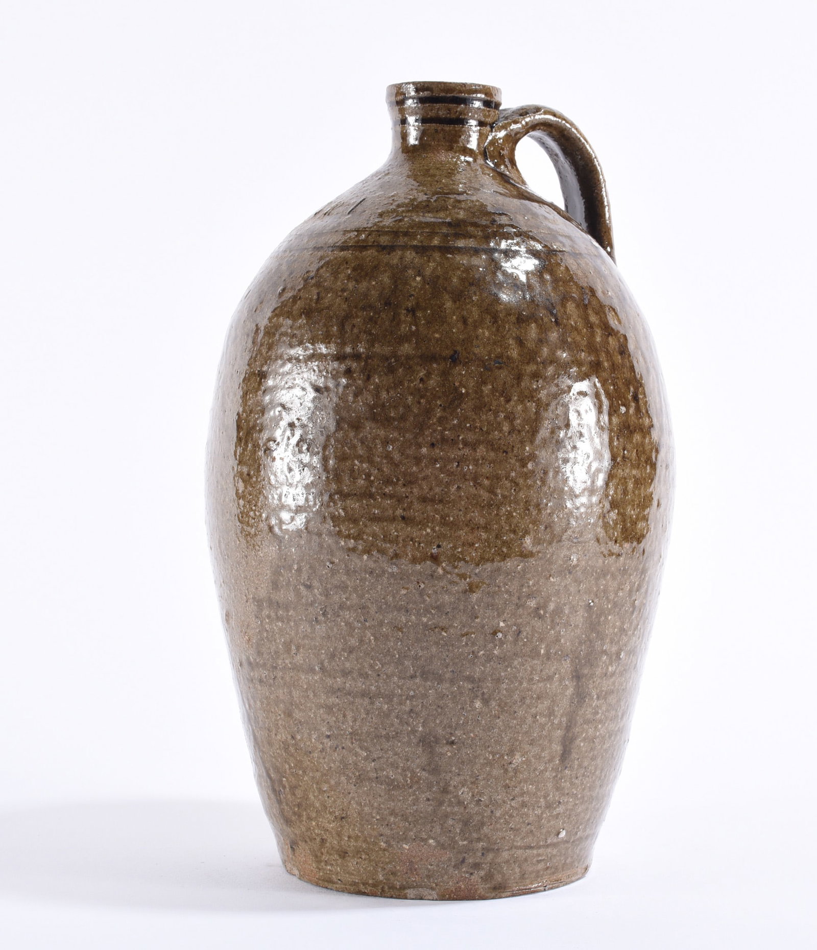 Thomas Ritchie Signed North Carolina Jug: Thomas Ritchie (1825–1909), Lincoln County, North Carolina, signed alkaline-glazed stoneware jug of tall ovoid form with tooled neck, applied loop handle and warm brown-to-olive glaze exhibiting cha