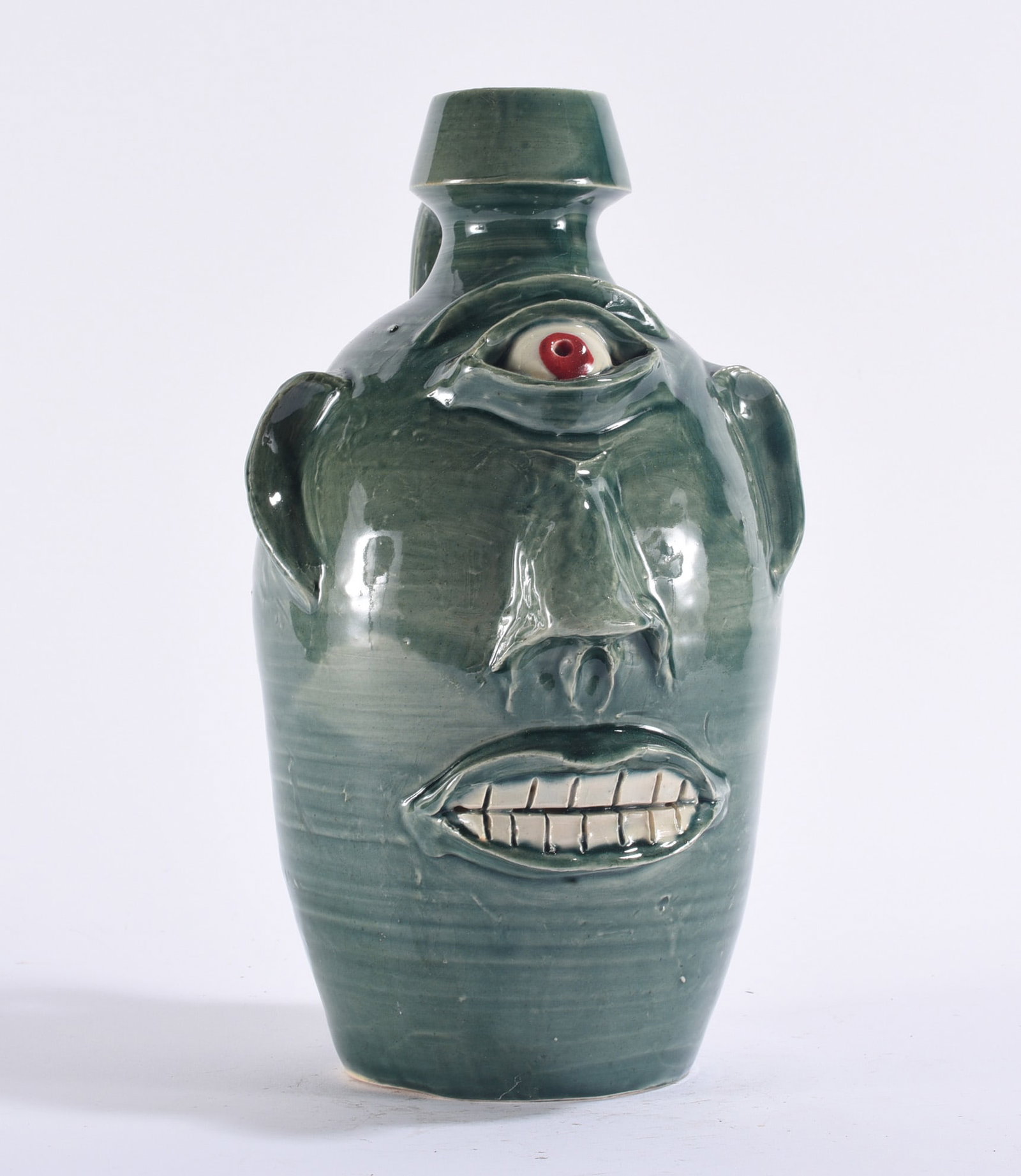 Randy Tobias Cyclops Face Jug: Randy Tobias North Carolina folk pottery cyclops face jug, wheel-thrown with tall cylindrical body and a single large red-and-white eye centered high on the forehead beneath a modeled brow. Additional