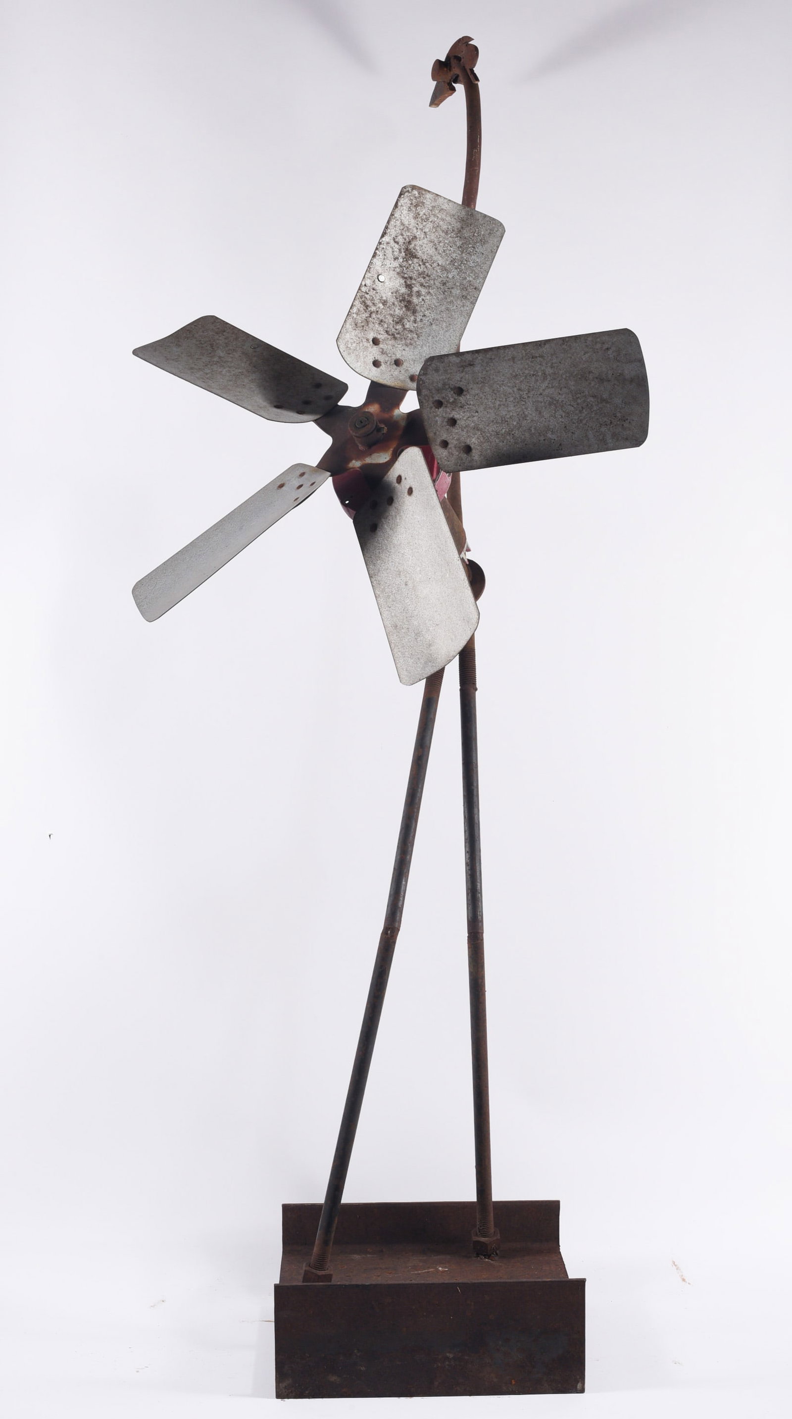 Folk Art Environmental Fan: Folk art environmental fan sculpture constructed from salvaged metal, featuring five fan blades mounted to a handmade figural frame with elongated legs and a rectangular iron base. The use of repurpos