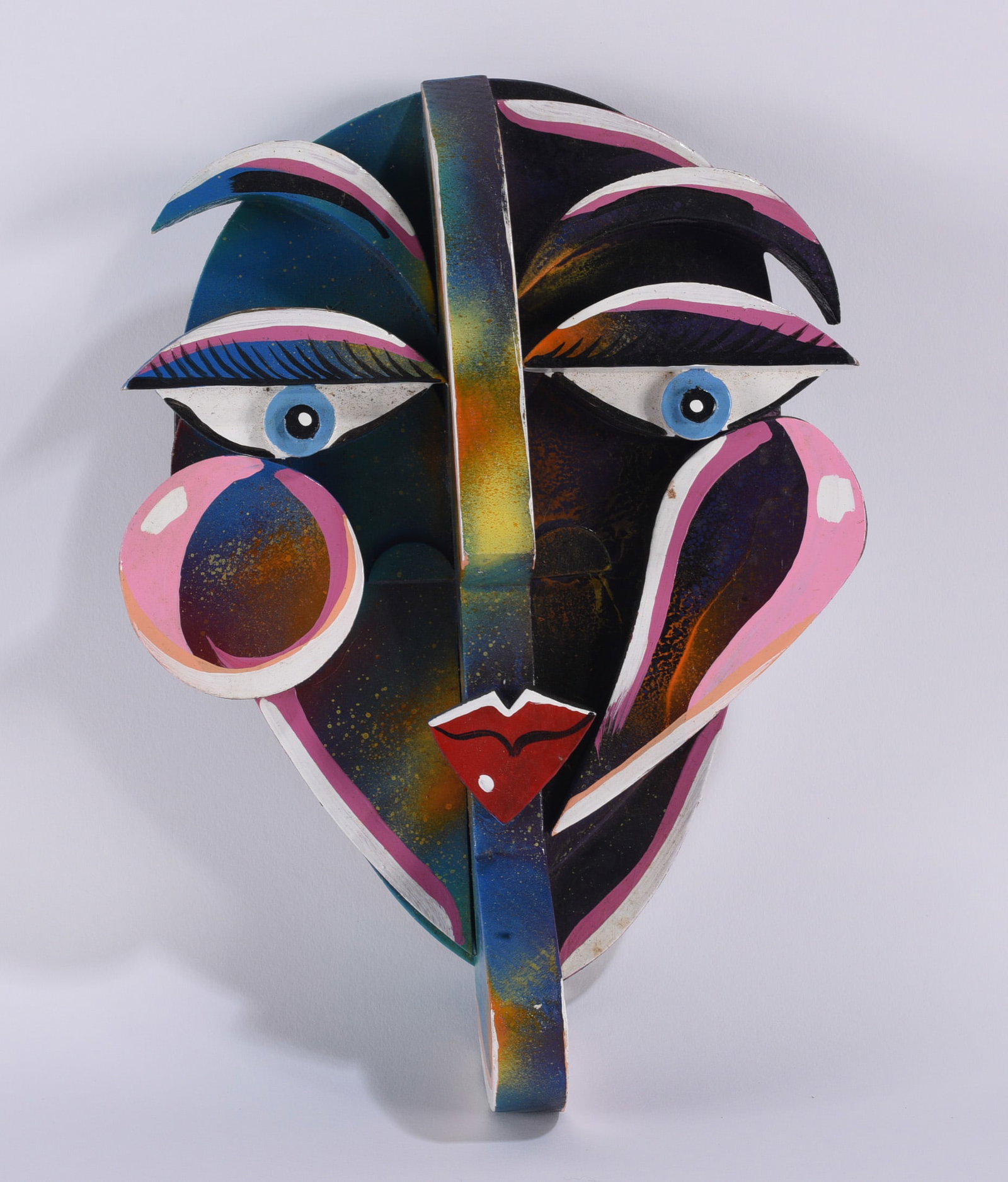 Joe Derr Folk Art Cubist Mask: Folk art Cubist-style mask by Joe Derr, constructed in relief with layered and projecting elements forming an abstract human face. Painted in black, blue, pink, white, red, and metallic tones, with