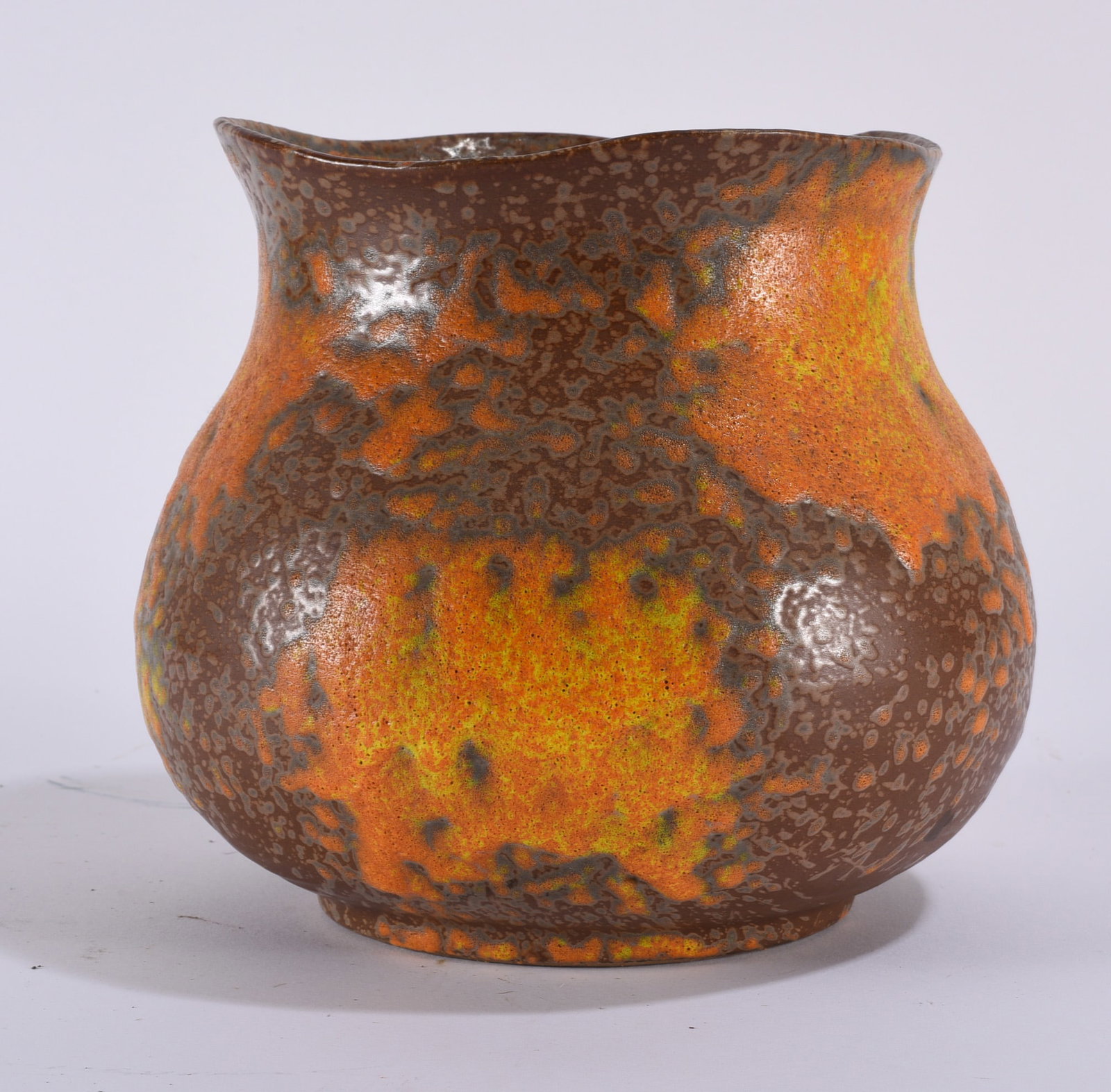 Royal Haeger Vase: Royal Haeger ceramic vase with rounded bulbous body, slightly pinched waist, and gently undulating rim. Finished in a dramatic mottled glaze combining brown, orange, yellow, and darker volcanic-like