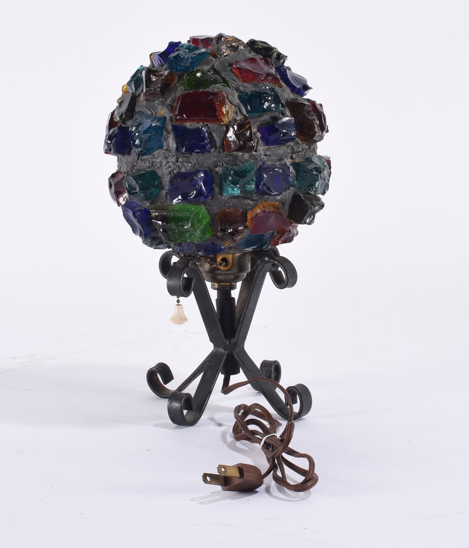 Peter Marsh Table Lamp: Peter Marsh table lamp featuring an irregular domed shade constructed from multicolored chunks of glass set within a dark matrix. Supported on a black metal base with curled scroll feet and fitted