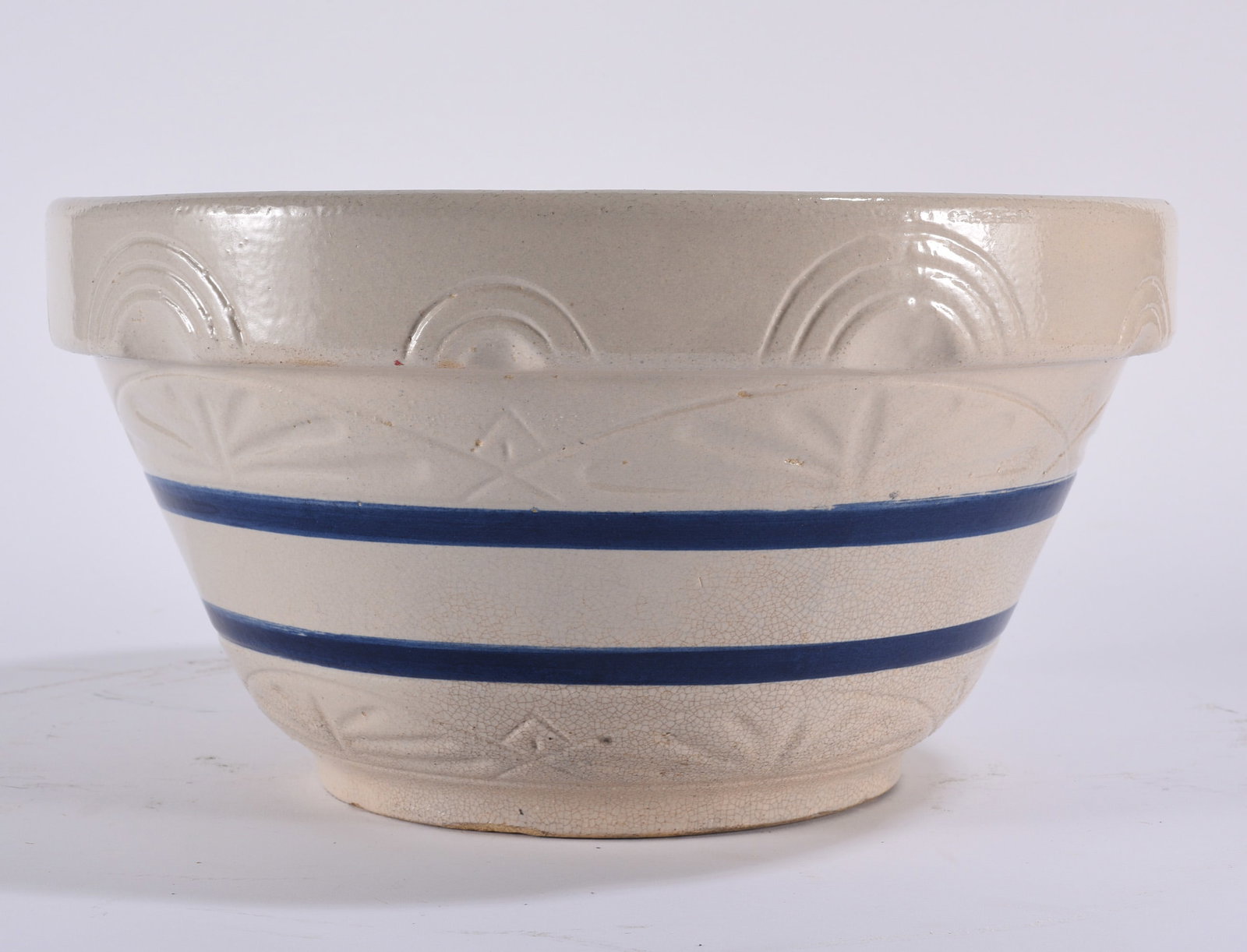 Robinson and Ransbottom Roseville Mixing Bowl: Antique stoneware mixing bowl with cream-colored glazed body, molded decorative bands and two cobalt-blue horizontal stripes. The bowl has a broad rolled rim, rounded form and footed base, with