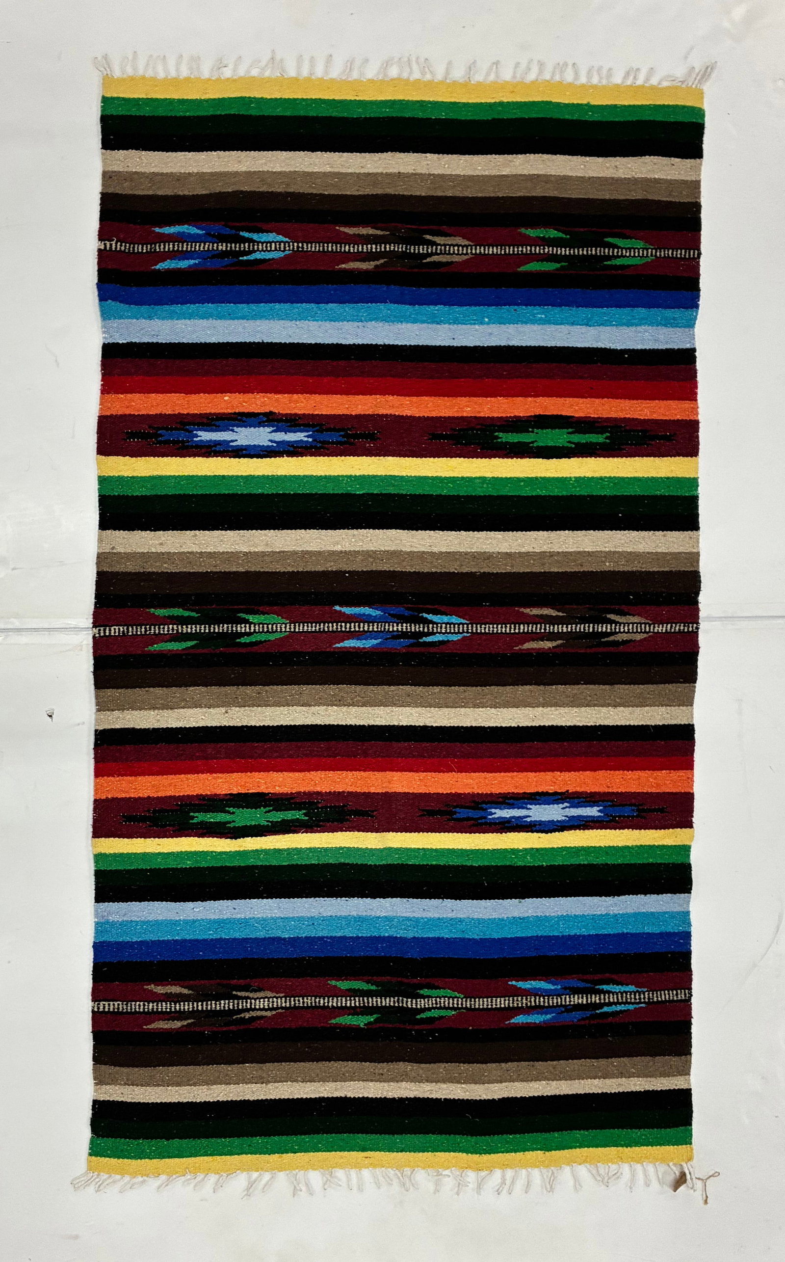 Southwestern Style Handwoven Striped Textile Rug: 78"x44" Colorful handwoven textile featuring broad horizontal bands of red, blue, green, yellow, black, brown and cream interspersed with geometric diamond and stepped motifs. Finished with fringe at 