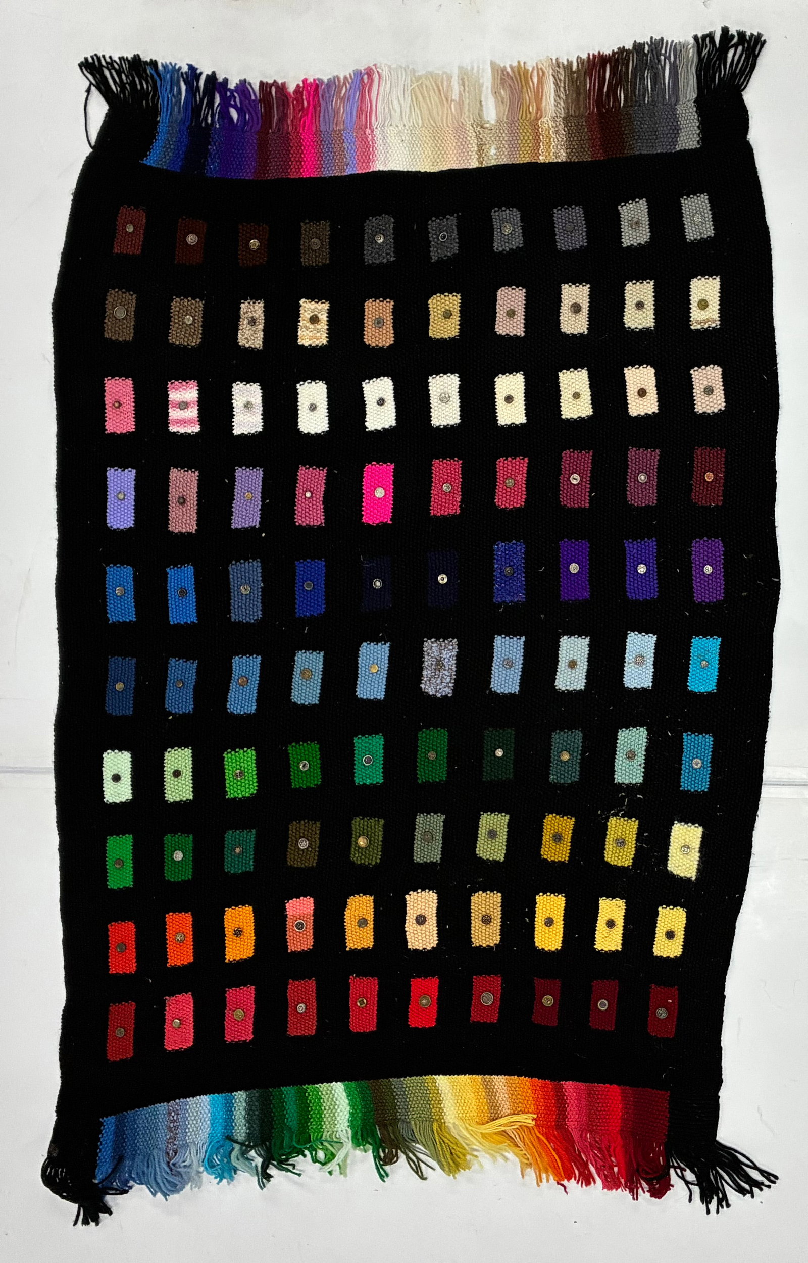 Handwoven Rainbow Throw Textile with Applied Buttons: 62"x40" Unusual handwoven textile worked on a black ground with rows of small rectangular woven color samples progressing through browns, creams, pinks, purples, blues, greens, yellows, oranges and re