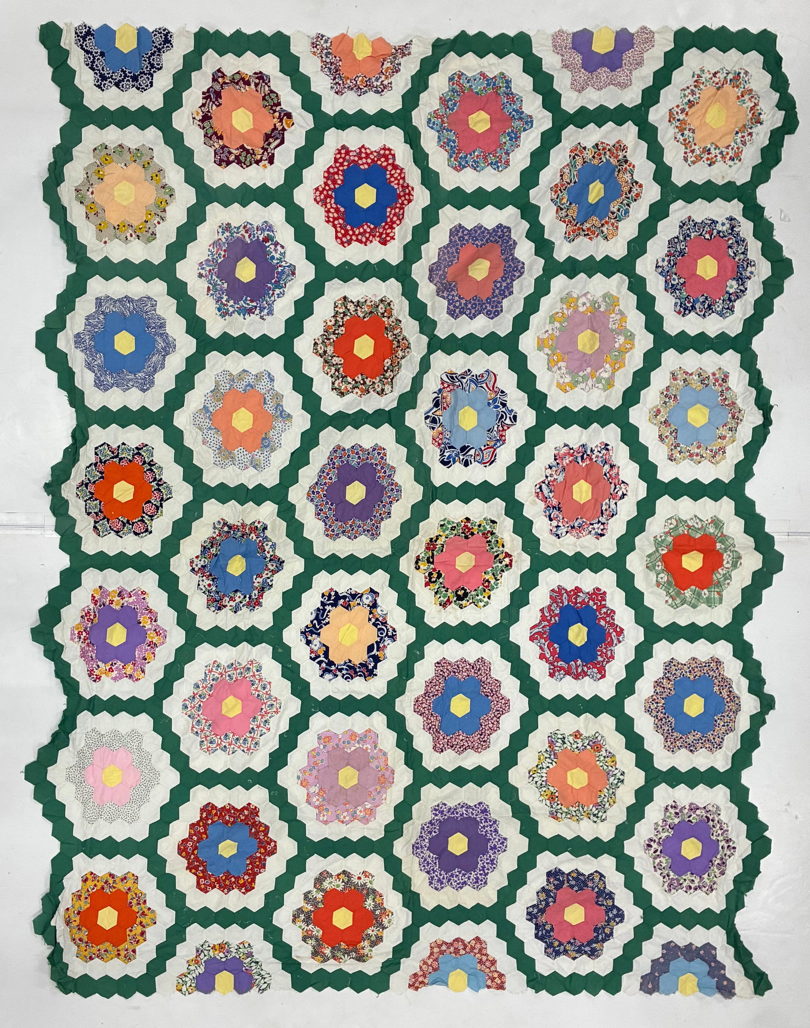 American Grandmother's Flower Garden Hexagon Quilt Topper: 82"x76" American hexagon quilt constructed in the classic Grandmother's Flower Garden tradition, with numerous individually colored floral rosettes composed of solid and printed cottons. Yellow hexago