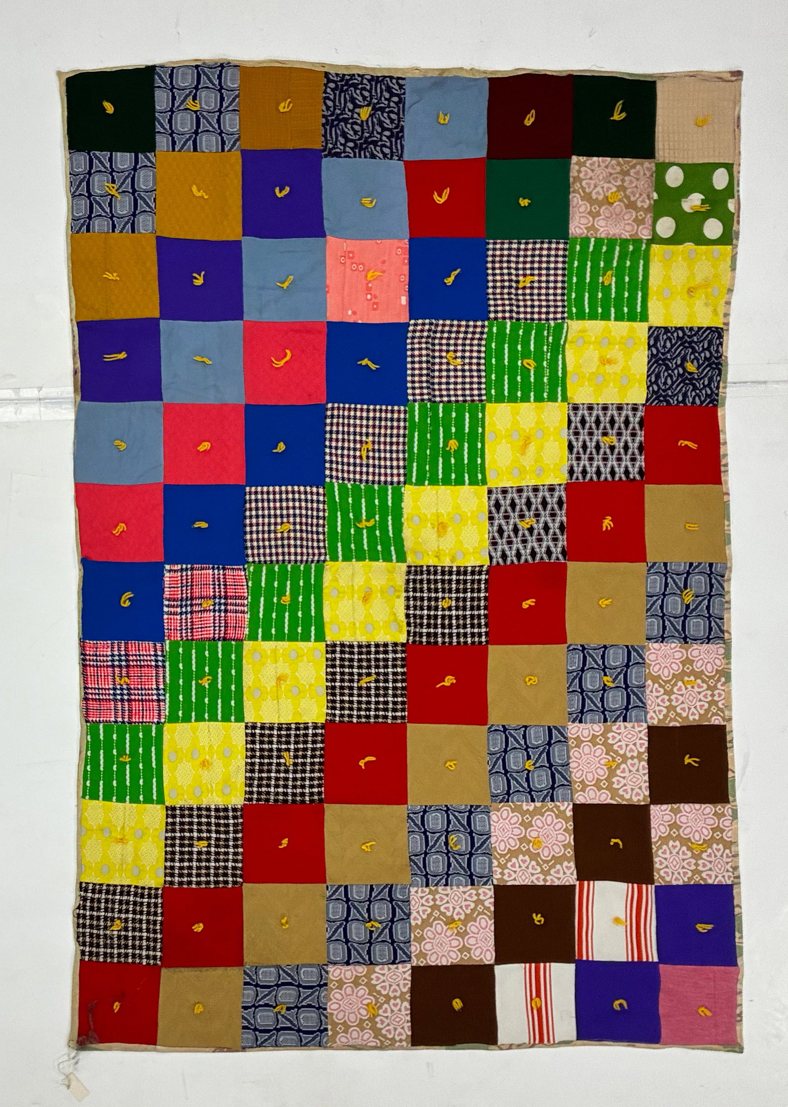 Early 20th Century American Tied Patchwork Utility Quilt: 56"x38" Early 20th century American utility quilt composed of a regular grid of large square patches in vivid solid colors, plaids, checks and geometric printed fabrics. Each square is individually se