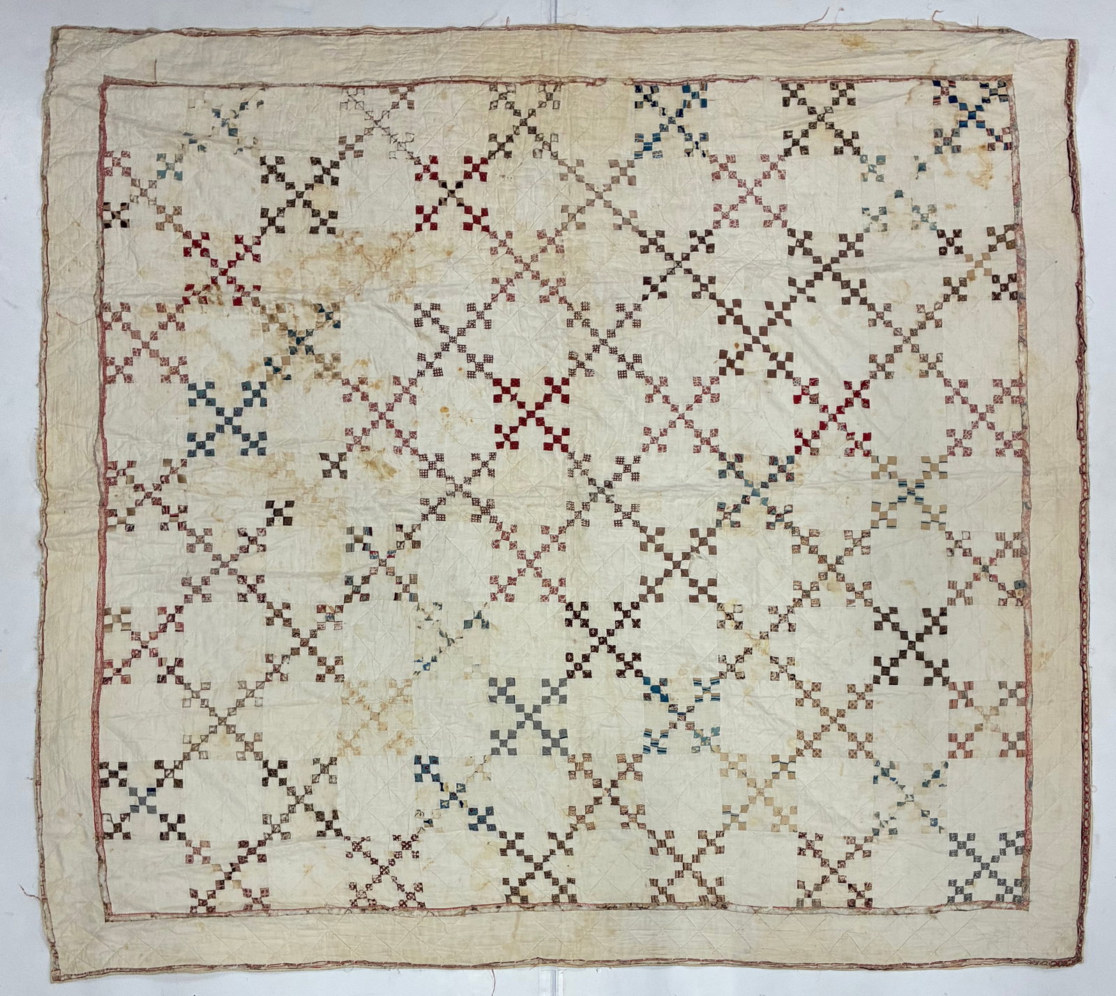 Early 20th Century American Irish Chain Variation Scrap Quilt: 79"x74" Early 20th century American scrap quilt constructed from tiny colored squares arranged against a predominantly cream ground to create an interlocking chain-like geometric pattern. Small red, b