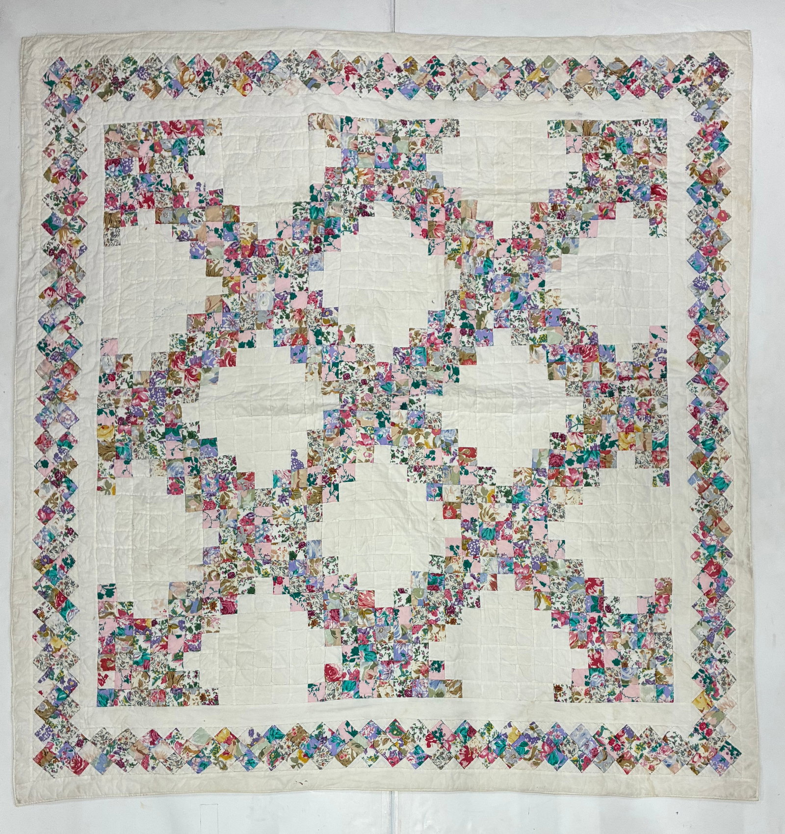 American Floral Scrappy Irish Chain Quilt: 81"x77" American scrap quilt related to the Irish Chain tradition, composed of hundreds of small floral-print cotton squares arranged into broad diagonal chains against a white ground. The colorful pr