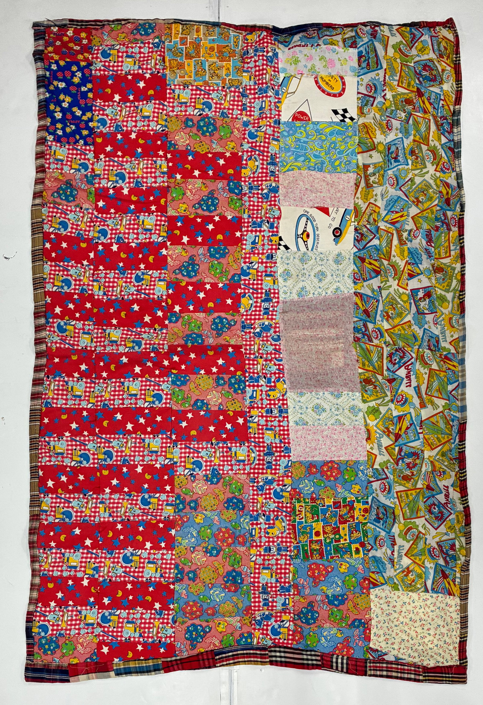 American Novelty Print Improvisational Patchwork Quilt: 48"x76" American improvisational utility quilt constructed from an exuberant assortment of brightly colored novelty and juvenile-print cotton fabrics. Red, blue and multicolored sections include stars