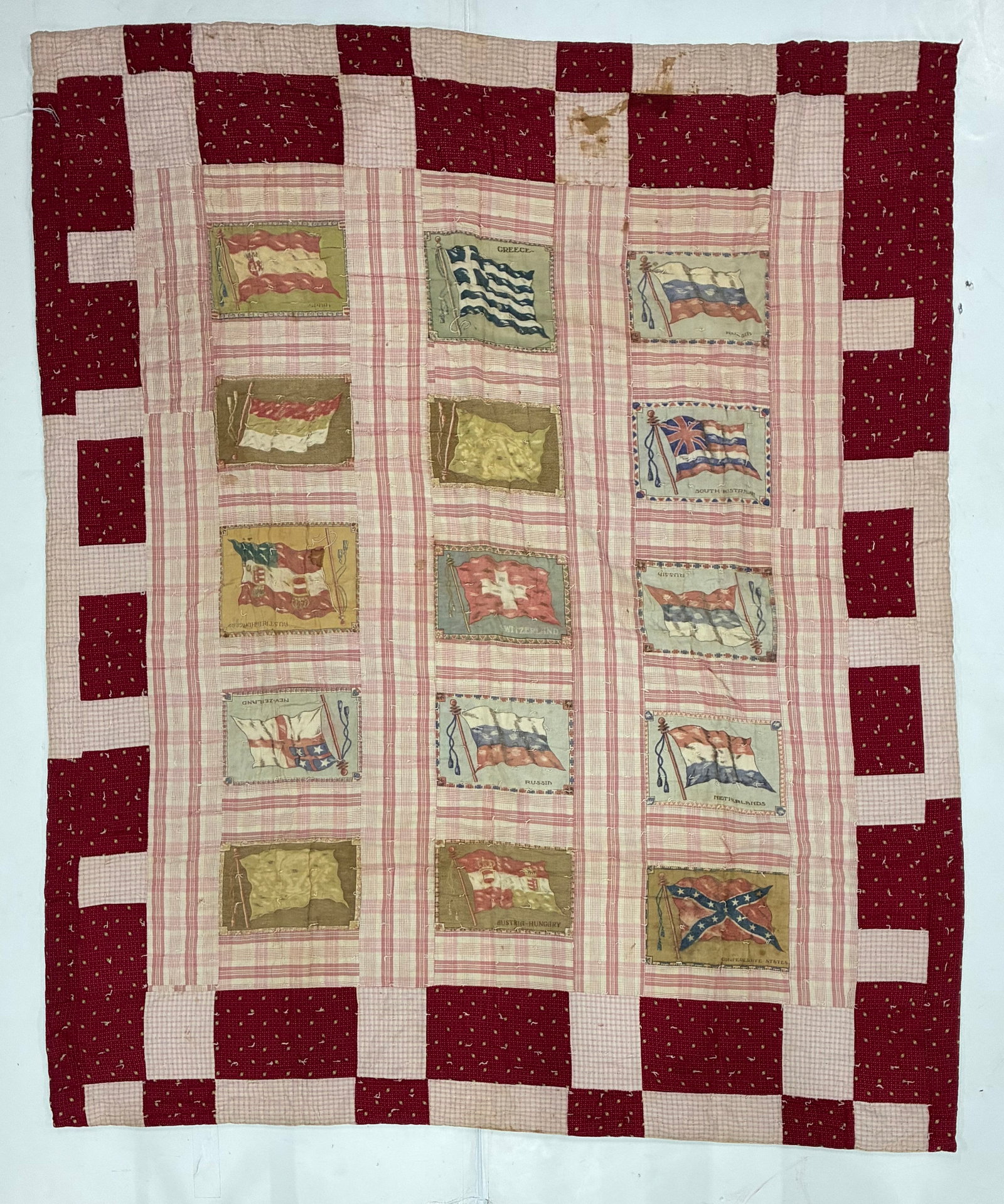 Early 20th Century International Flag & Textile Novelty Quilt: 64"x74" Early 20th century American novelty quilt incorporating printed textile panels depicting international and historic flags arranged against a pink-and-cream plaid ground. Visible examples