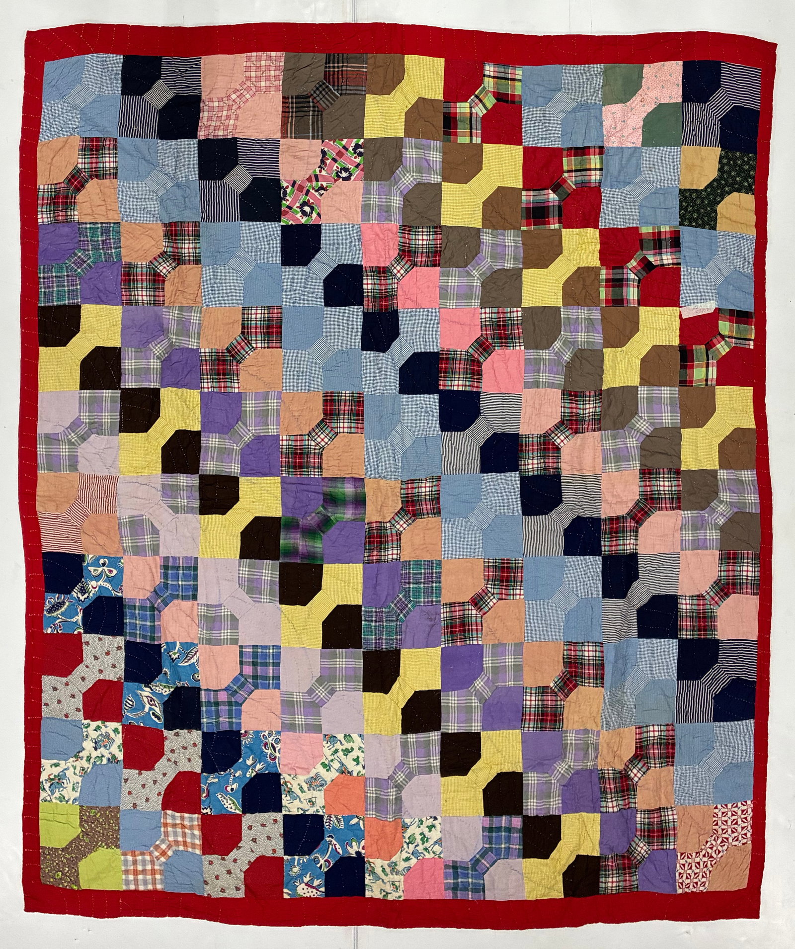 American Bow Tie Scrap Quilt with Red Border: 67"x75" American scrap quilt featuring a repeating Bow Tie pattern assembled from an extensive assortment of plaids, checks, stripes, florals and solid fabrics. Blocks in blue, pink, purple, yellow, b
