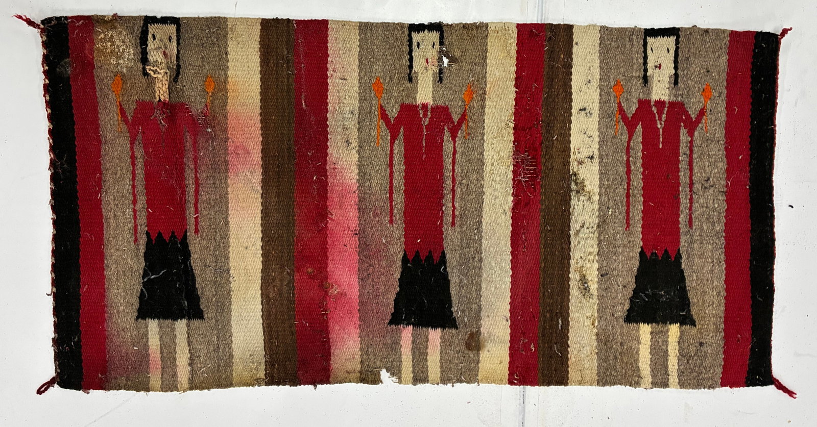 Southwestern Figural Woven Rug with Three Female Figures: 35"x18" Southwestern figural woven rug featuring three stylized female figures arranged across a striped ground in red, brown, cream and black. Each figure wears a long red garment with dark skirt and