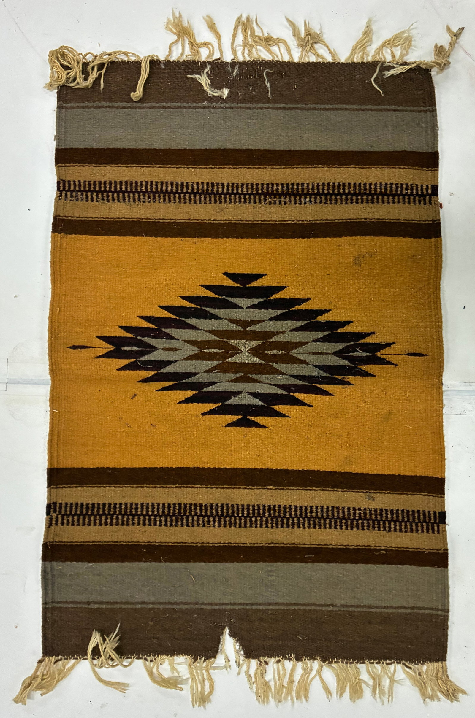 Southwestern Handwoven Stepped Diamond Textile: 34"x22" Handwoven textile featuring a bold central stepped-diamond motif in black, gray and brown against a mustard-yellow field. Horizontal bands of brown, gray and tan frame the composition above an