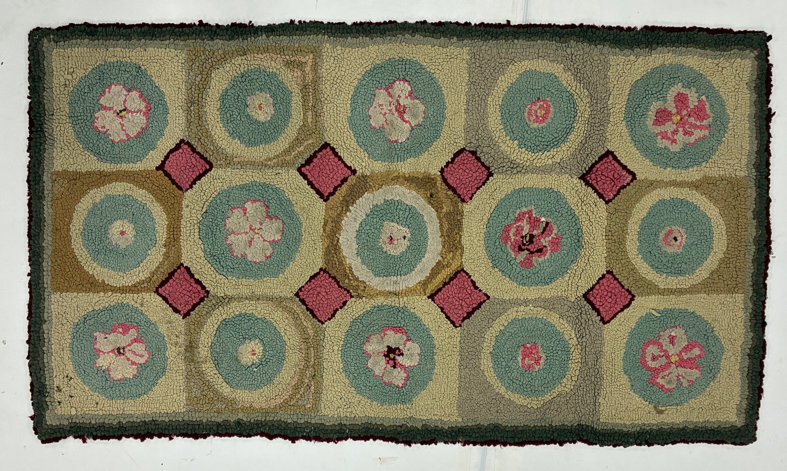 Vintage Floral Medallion Hooked Rug: 54"x30" Hand-hooked rug featuring repeating circular floral medallions in pale blue, cream and pink arranged across a tan and gray field. Small pink diamond motifs separate the larger circular