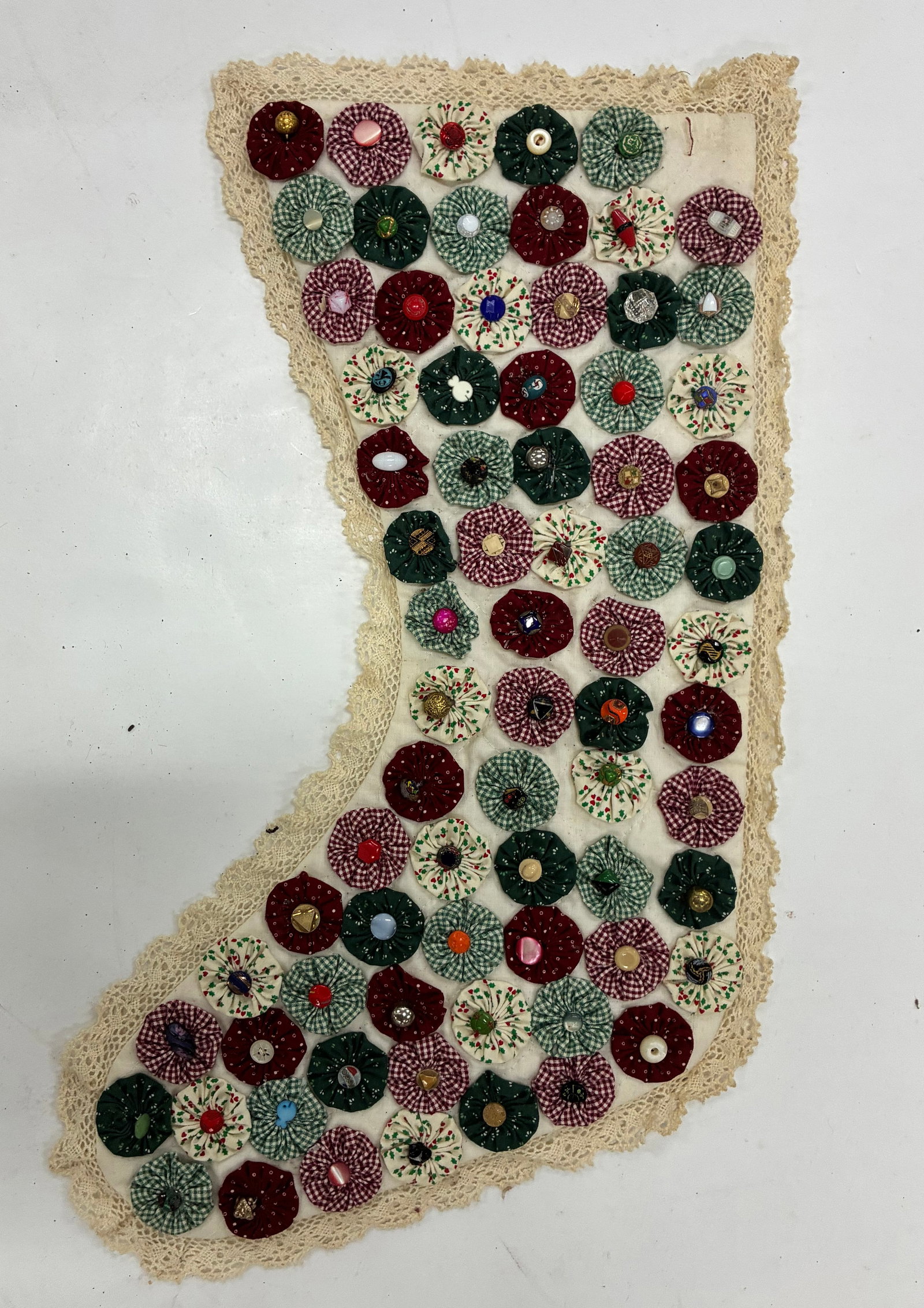 American Folk Art Yo-Yo and Button Textile: 11"x16" Handmade folk art textile composed of dozens of gathered fabric yo-yos individually centered with assorted vintage buttons. Fabrics include red and green prints, ginghams and small patterned