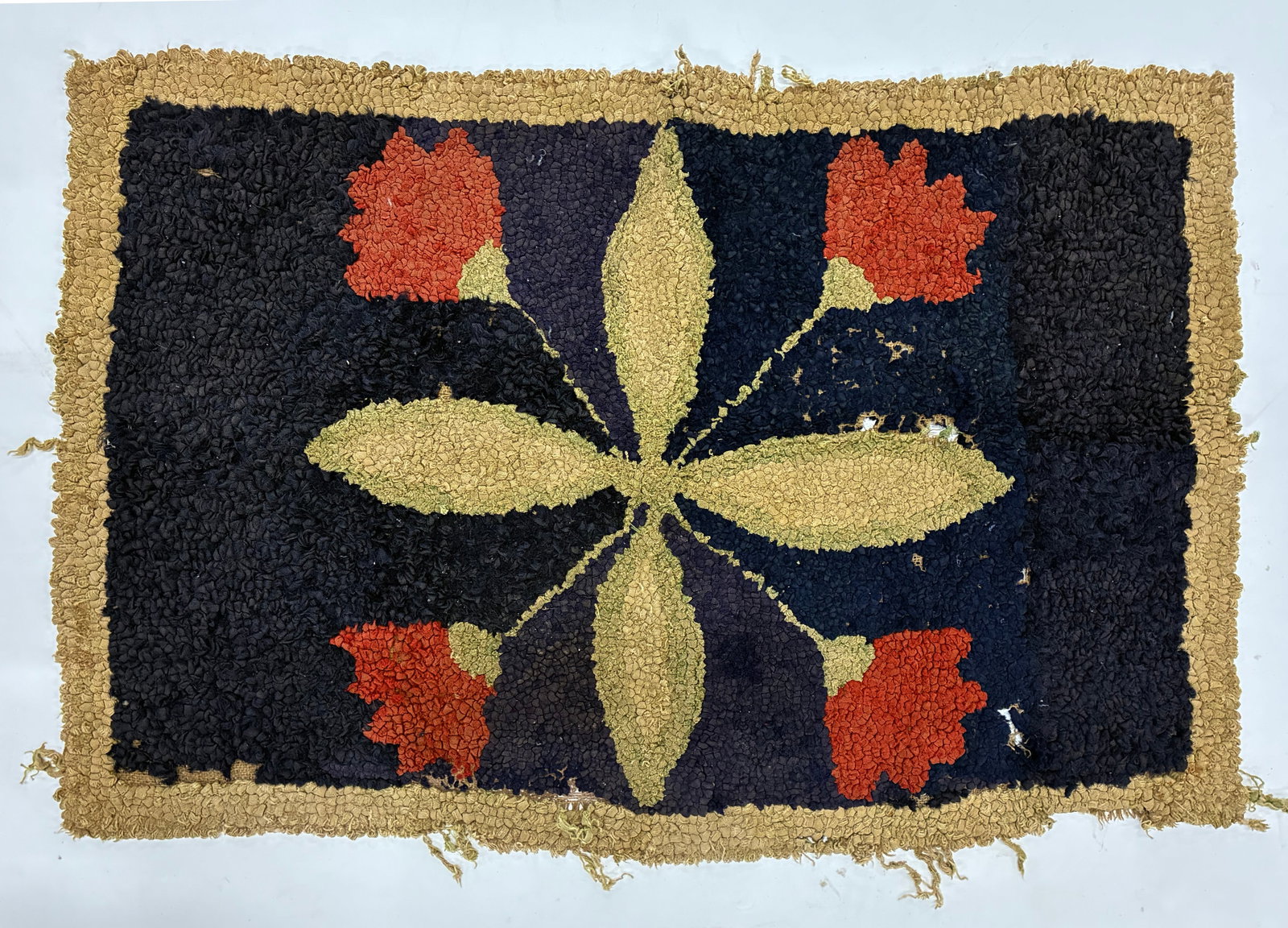 Vintage Floral Folk Art Hooked Rug: 37"x24" Hand-hooked rug featuring four stylized red-orange flowers with broad yellow-green leaves arranged symmetrically against a deep black and dark blue field. A wide tan border surrounds the