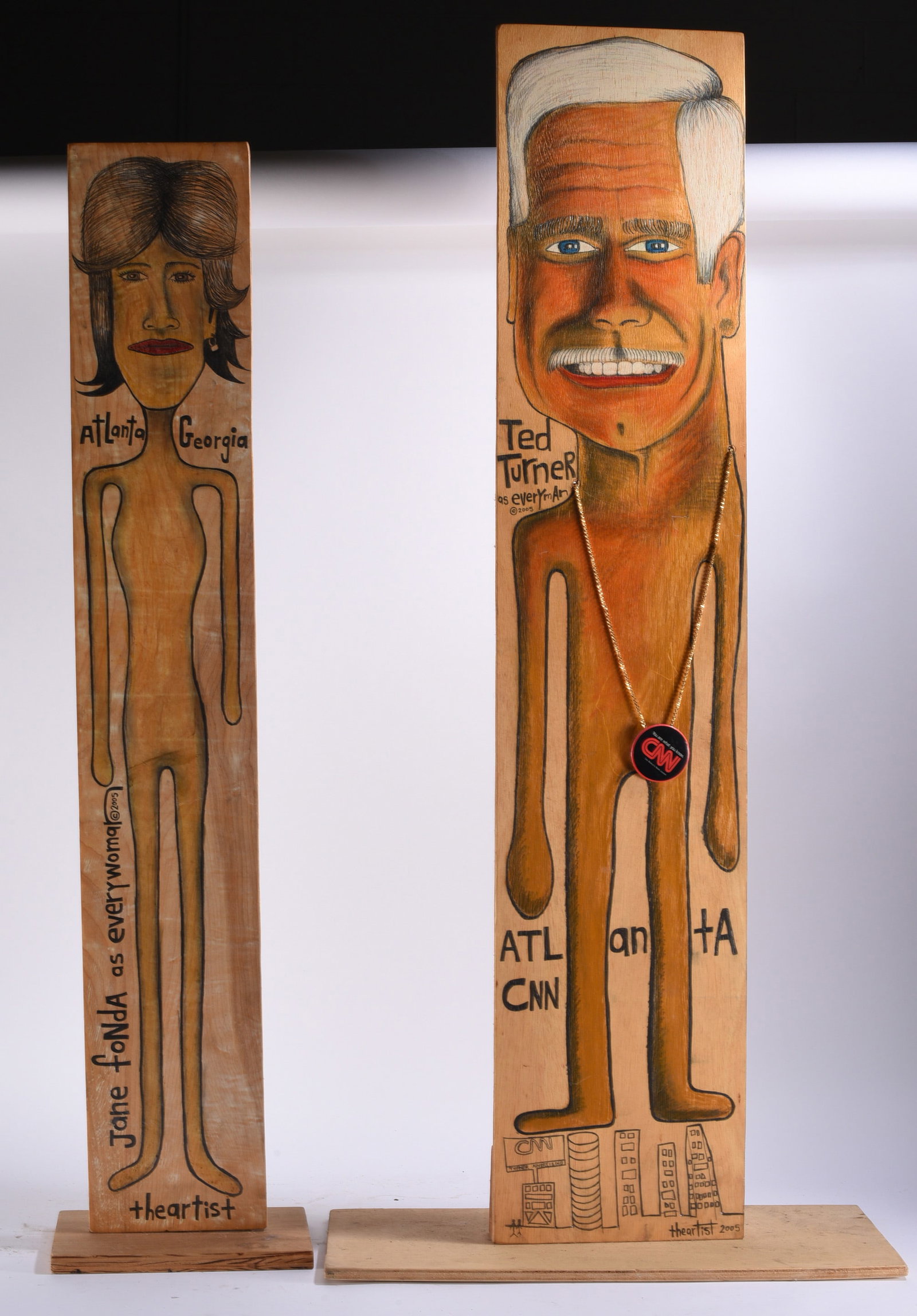 Folk Art by "The Artist" Winterville, GA: Largest 23"x48" Folk art by the artist known as “The Artist” of Winterville, Georgia, consisting of two tall hand-drawn and painted wooden portrait figures. One depicts Jane Fonda with “Atlanta 