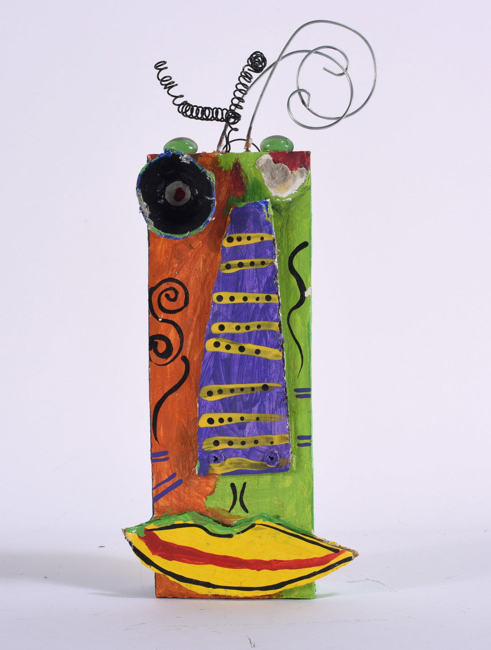 Contemporary Folk Art Mixed Media Face Sculpture: 5"x12" Colorful contemporary folk art assemblage sculpture depicting an abstract face, constructed from painted wood and mixed media with applied dimensional elements, coiled wire hair or antennae, gl
