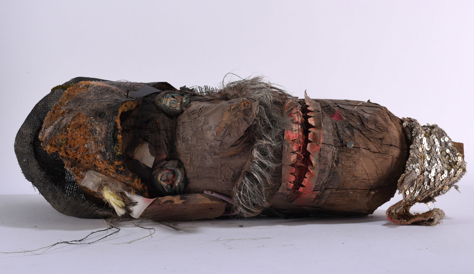 Primitive Folk Art Carved Wood Figural Sculpture: 8"x25" Primitive folk art figural sculpture fashioned from a naturally weathered section of wood and embellished with found materials, fabric, hair, painted details and applied elements. The expressiv