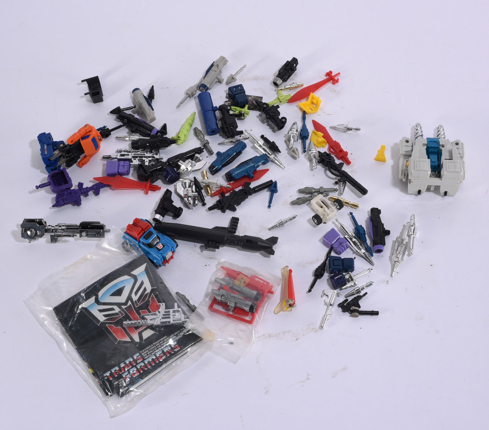 Vintage Transformers Toy Parts & Accessories Collection: Ships in 10"x10"x10" Collection of vintage Transformers toy parts, weapons and accessories in assorted colors and forms, including numerous miniature guns, missiles, mechanical components and other pi