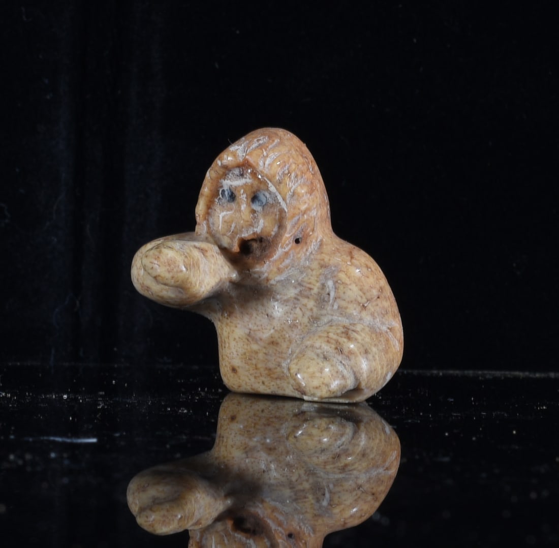 Inuit Carved Bone Sea Otter Figure: 1" Inuit carved bone sea otter figure depicted reclining on its back with paws resting across the body. Hand carved with dark accents defining the eyes and claws and a smoothly polished cream-colored 