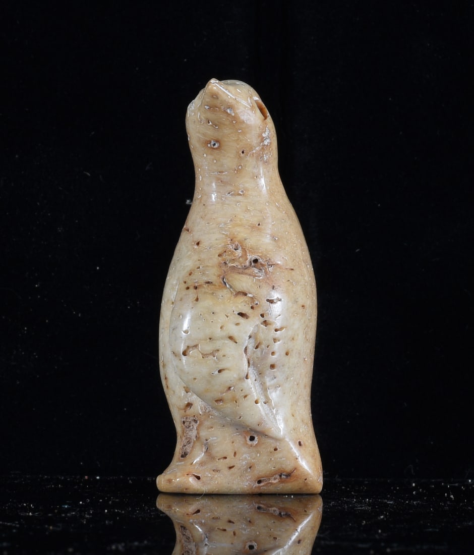 Inuit Carved Bone Seal Figure: 2" Inuit carved bone seal figure depicted upright with elongated body and simplified flippers. Hand carved and polished with natural cream and tan coloration and scattered porous areas throughout the 