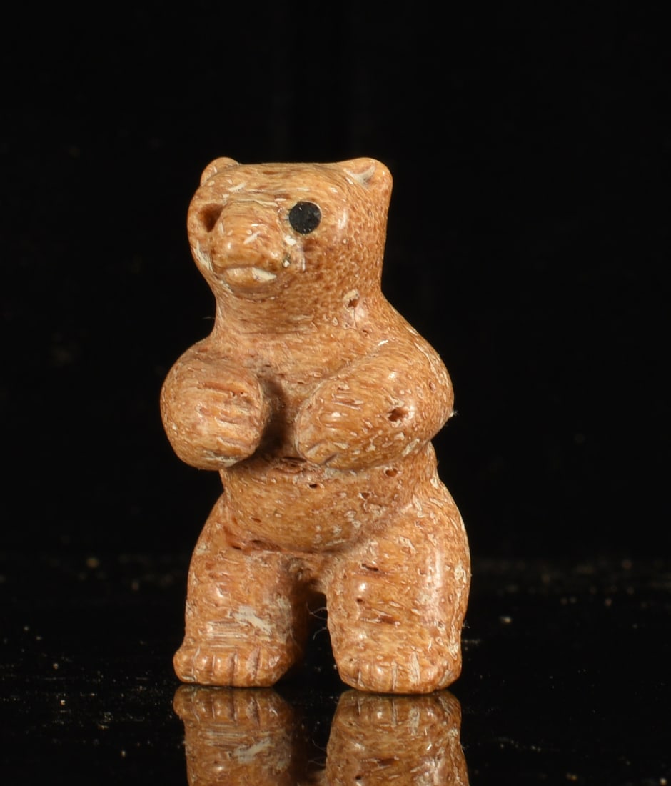 Inuit Carved Bone Standing Bear Figure: 1.5" Inuit carved bone standing bear figure with raised forepaws, rounded body and inset dark eye. Warm brown coloration with incised fur details and natural porous areas.