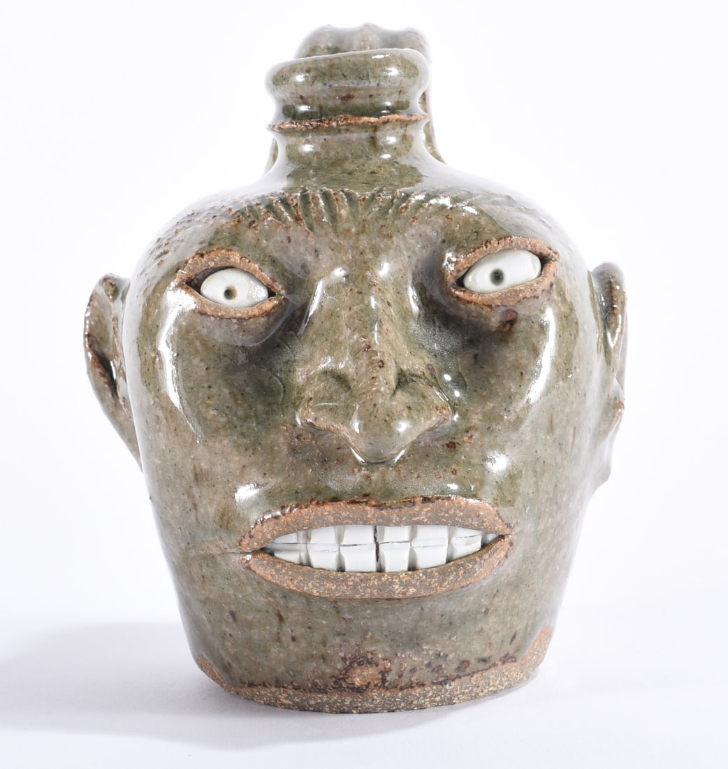 Michele Bayne Miniature Face Jug: Michele Bayne miniature folk pottery face jug with rounded body, rear strap handle, strongly arched brows, inset white eyes, modeled ears and nose, and a broad grinning mouth filled with individually