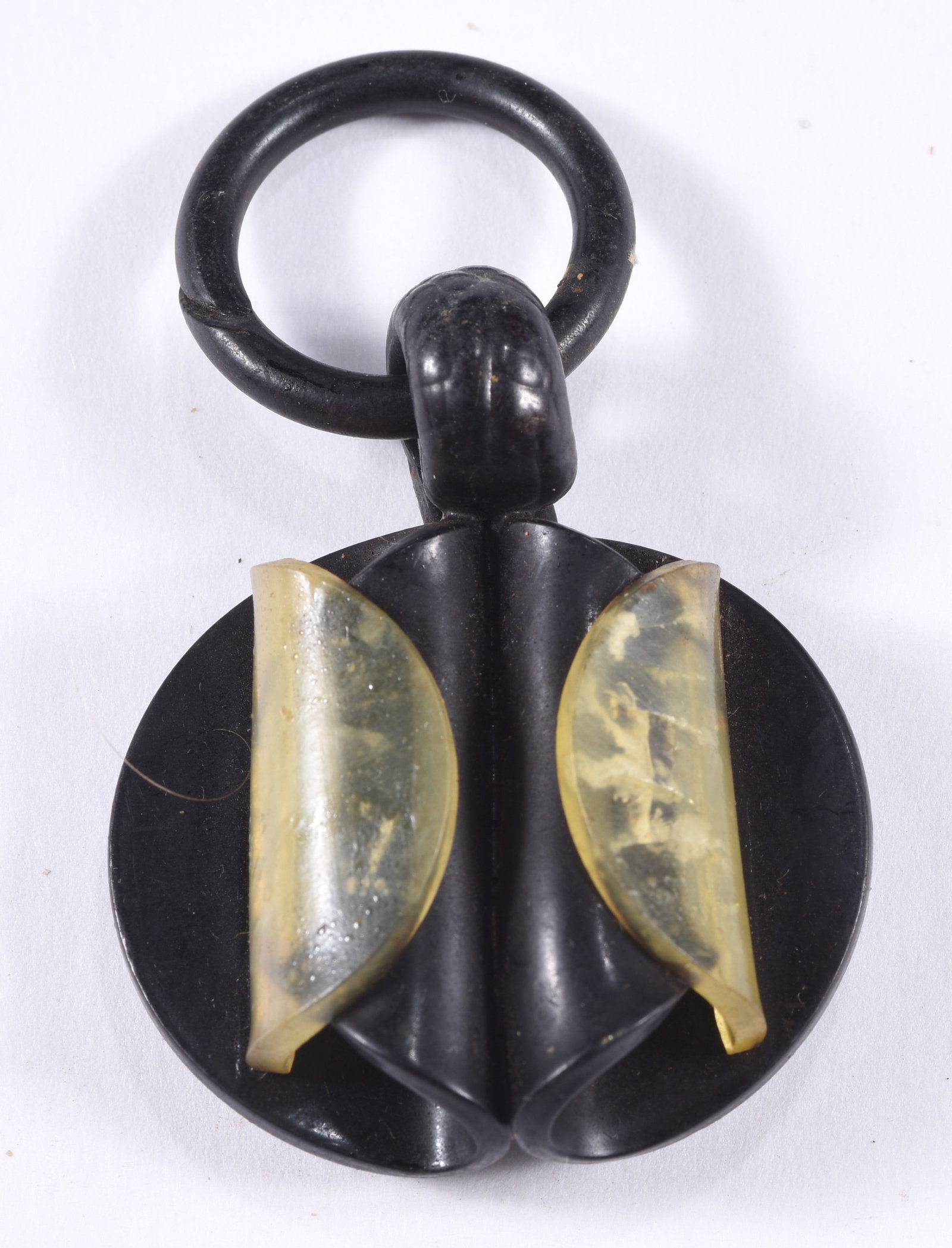Vintage Art Deco Black & Translucent Plastic Toggle Fastener: Unusual vintage Art Deco black plastic garment fastener or toggle featuring a circular body with symmetrical geometric construction and two translucent amber-yellow curved inserts. Large integral ring