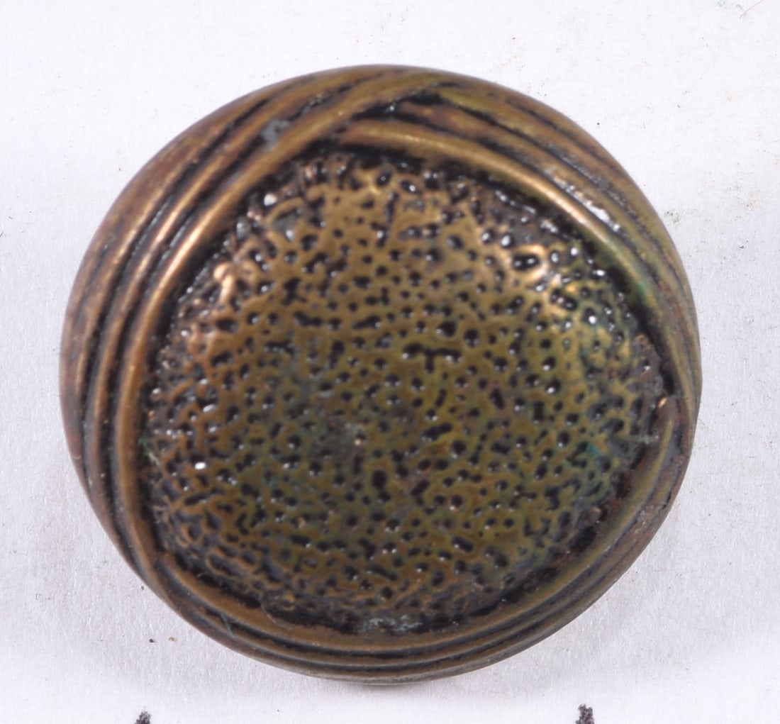 Antique Brass Agricultural & Hunting Motif Button: Antique brass-tone button with raised agricultural and sporting imagery including crossed implements, foliage and game motifs, surrounded by a decorative lettered border. Integral shank to reverse. Ap