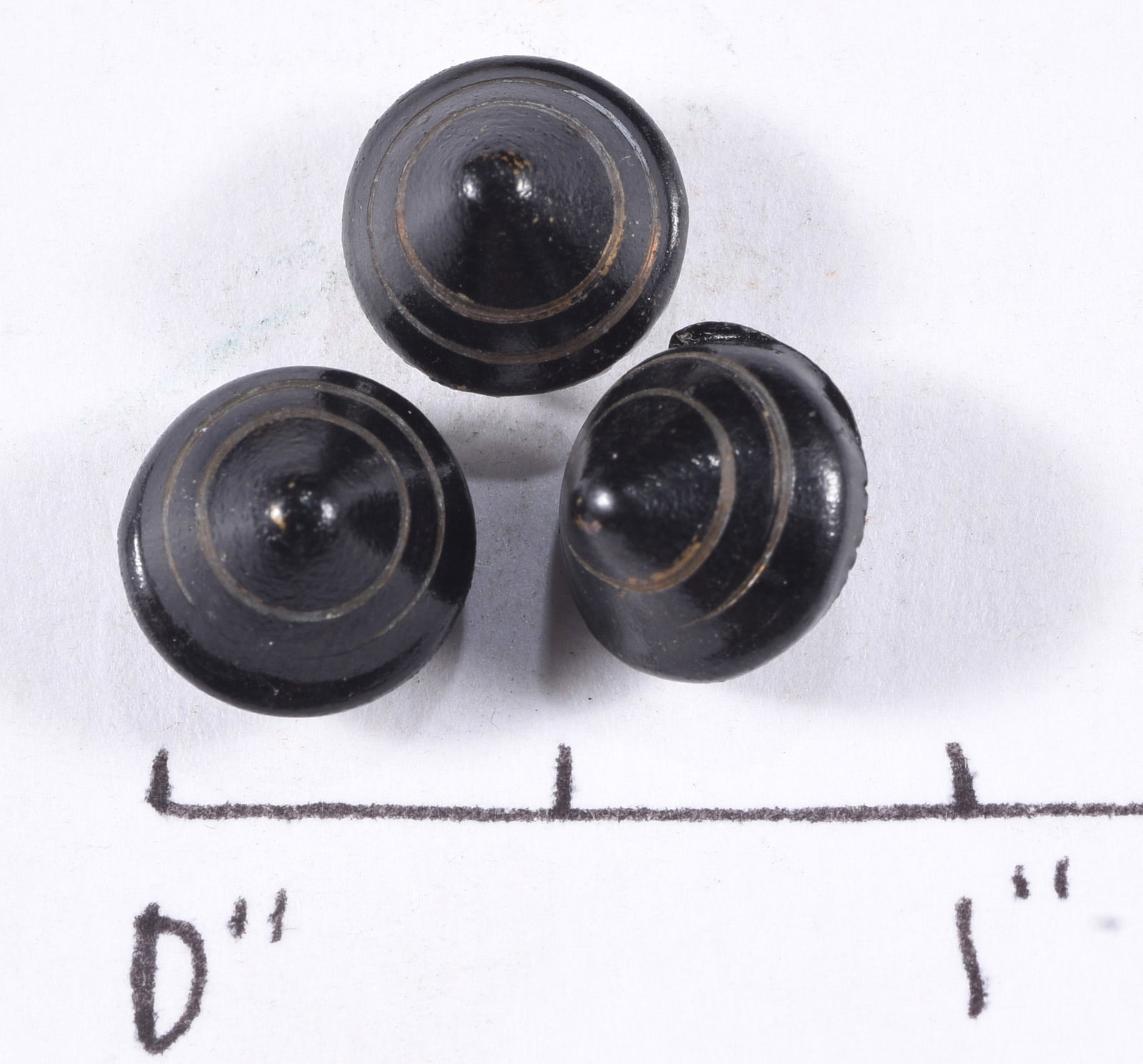Set of Three Antique Black Dome Buttons: Set of three antique black domed buttons with concentric incised rings and rounded central bosses. Backs appear to have integral or molded attachment openings rather than conventional exposed metal sh