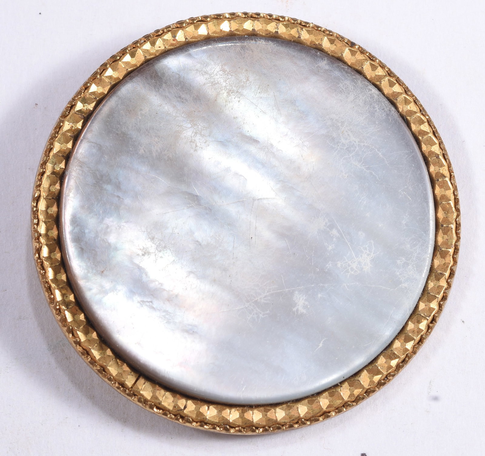 Large Mother-of-Pearl and Gilt Metal Button: Large round button featuring a luminous mother-of-pearl center surrounded by a faceted gilt-metal border. The shell displays attractive natural iridescence with expected surface wear.