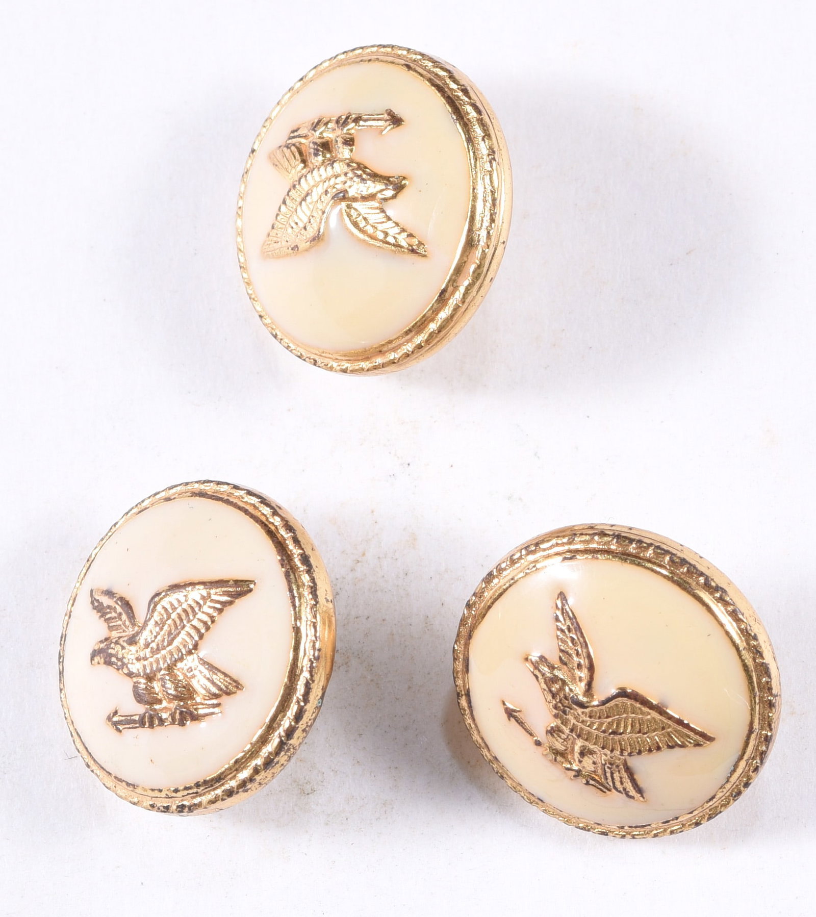 Set of Three Vintage Cream Enamel Eagle Buttons: Set of three vintage cream-colored buttons with raised gilt eagle motifs and decorative gilt borders. Each features a different eagle pose, creating an attractive coordinating patriotic group with lig