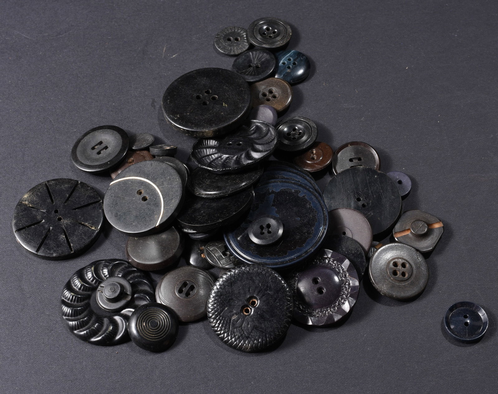 Large Collection of Vintage Black Buttons: Collection of vintage black and very dark navy buttons with numerous oversized decorative examples. Includes pierced sunburst designs, concentric-ring decoration, molded borders, domed and flat forms,