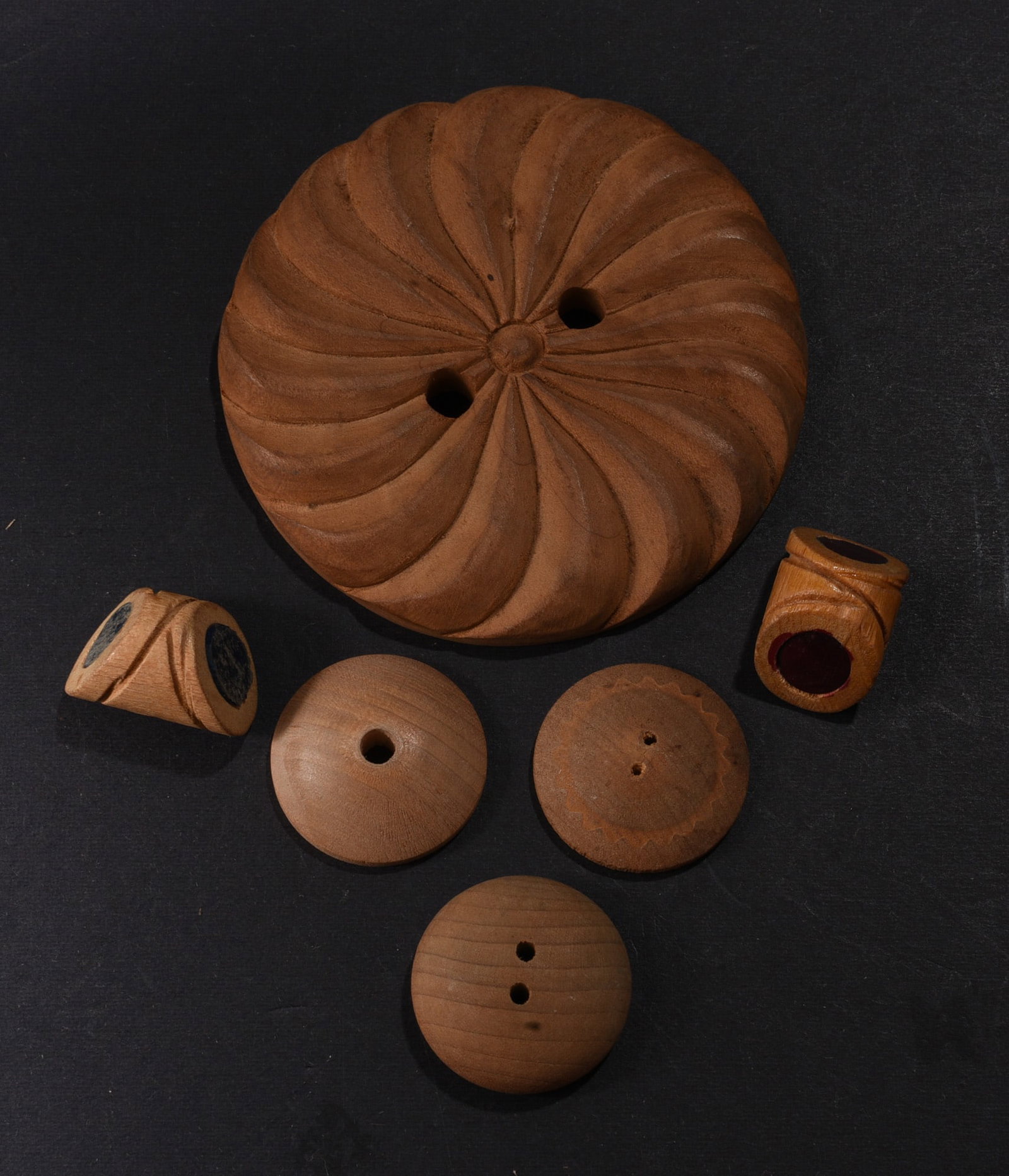 Collection of Antique Hand-Carved Wooden Buttons: Small collection of hand-carved and turned wooden buttons and related sewing pieces. Highlighted by an exceptionally large two-hole button carved with a radiating spiral or pinwheel pattern, accompani