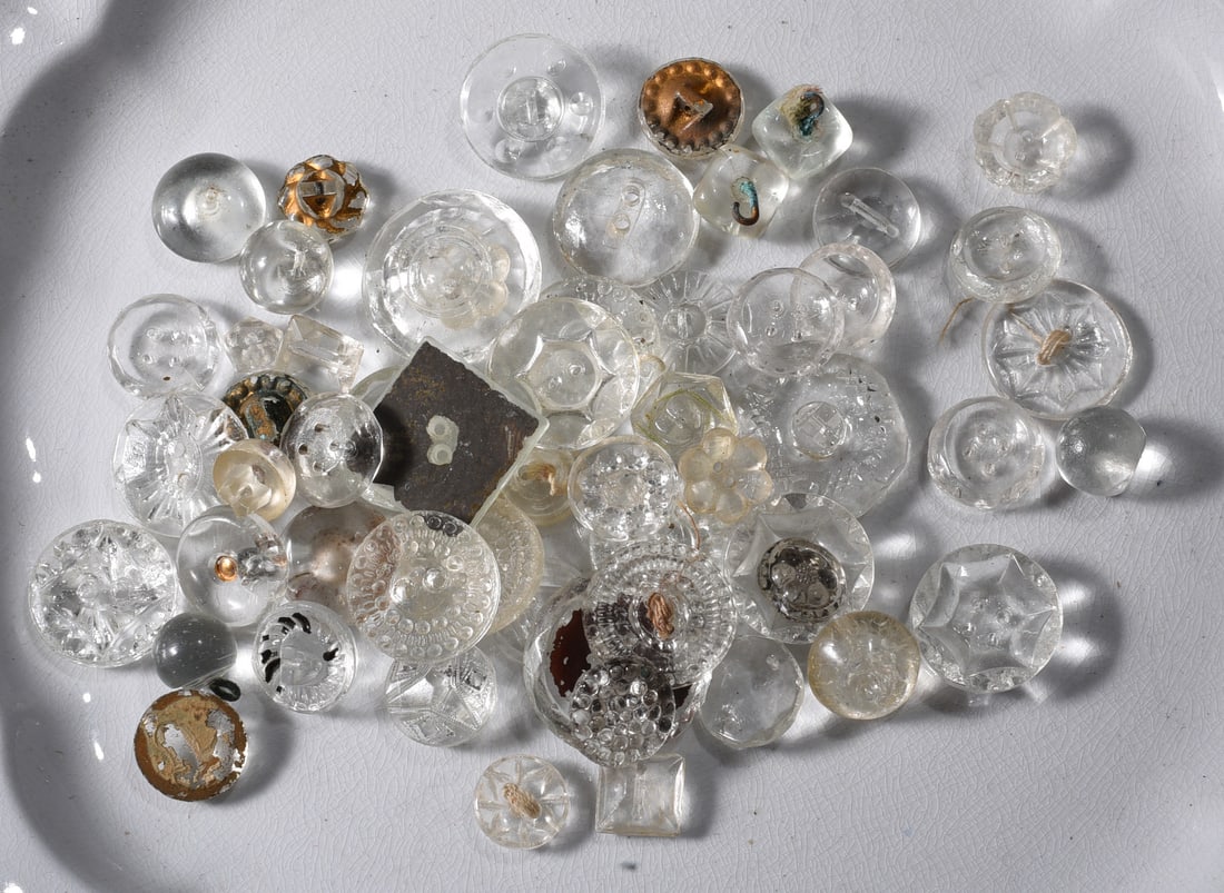 Collection of Antique Clear Glass Buttons: Collection of antique and vintage clear pressed-glass buttons in numerous sizes and designs. Includes faceted, floral, geometric, beaded and smooth examples with sew-through and shank construction. Va