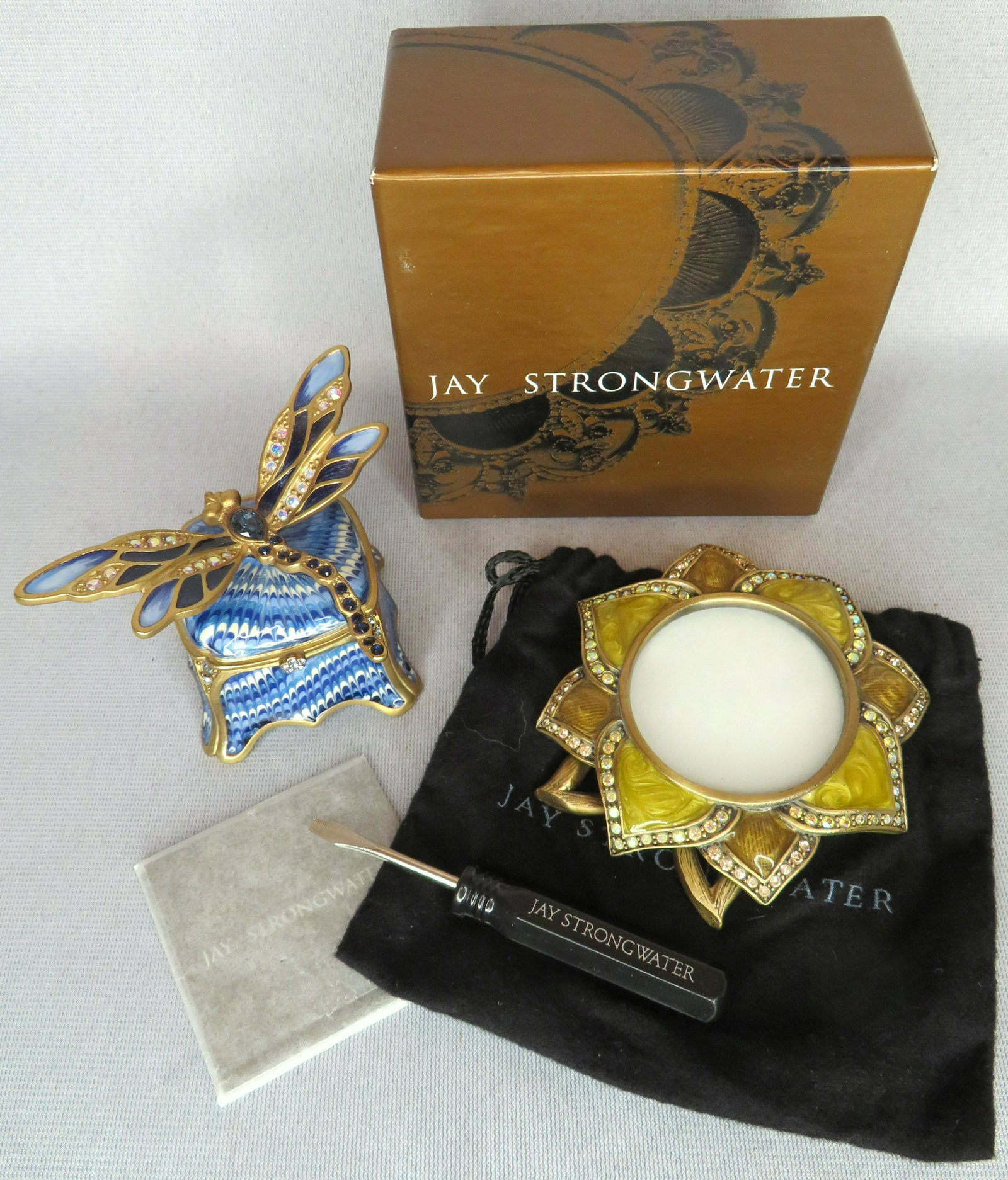 (2) Signed Jay Strongwater Bejeweled Enamel Articles: For your consideration is a Jay Strongwater frame and trinket or pill box. The floral form frame has beautiful chartreuse and gold enamel decorations and is embellished with brilliant aurora borealis 