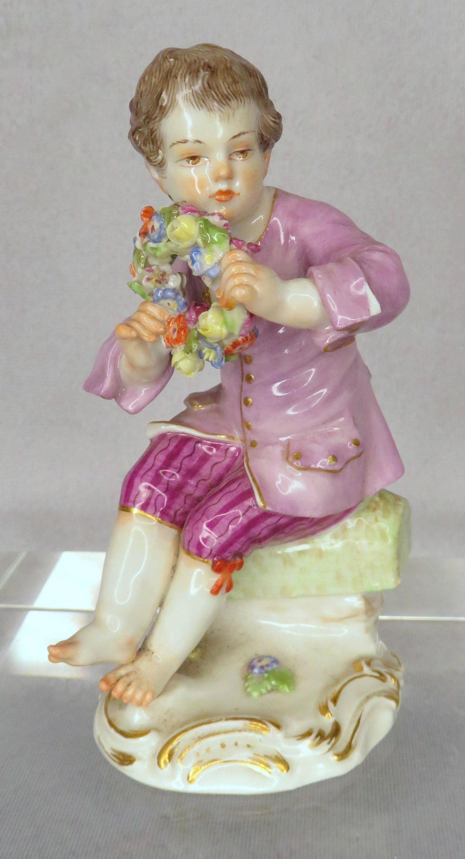 Meissen Porcelain Gardening Children Boy Wreath Figure: Manufacturer: Meissen Location of Manufacture: Germany Period of Manufacture: Early 20th Century Model Number: 106L / 15 Series: Gardening Children Designer: Johann Joackim Kaendler Dimensions: 4 3/4"
