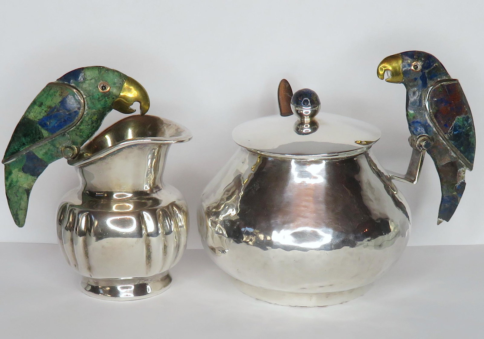 Los Castillos Inlaid Silver Parrot Creamer Sugar Bowl: Manufacturer: Los Castillos Location of Manufacture: Taxco, Mexico Dimensions of Lidded Sugar Bowl: 5" diameter ; 4 1/2"(h) Dimensions of Cream Pitcher: 3 1/2" diameter ; 4 1/4"(h) Weight of Set: 1 lb