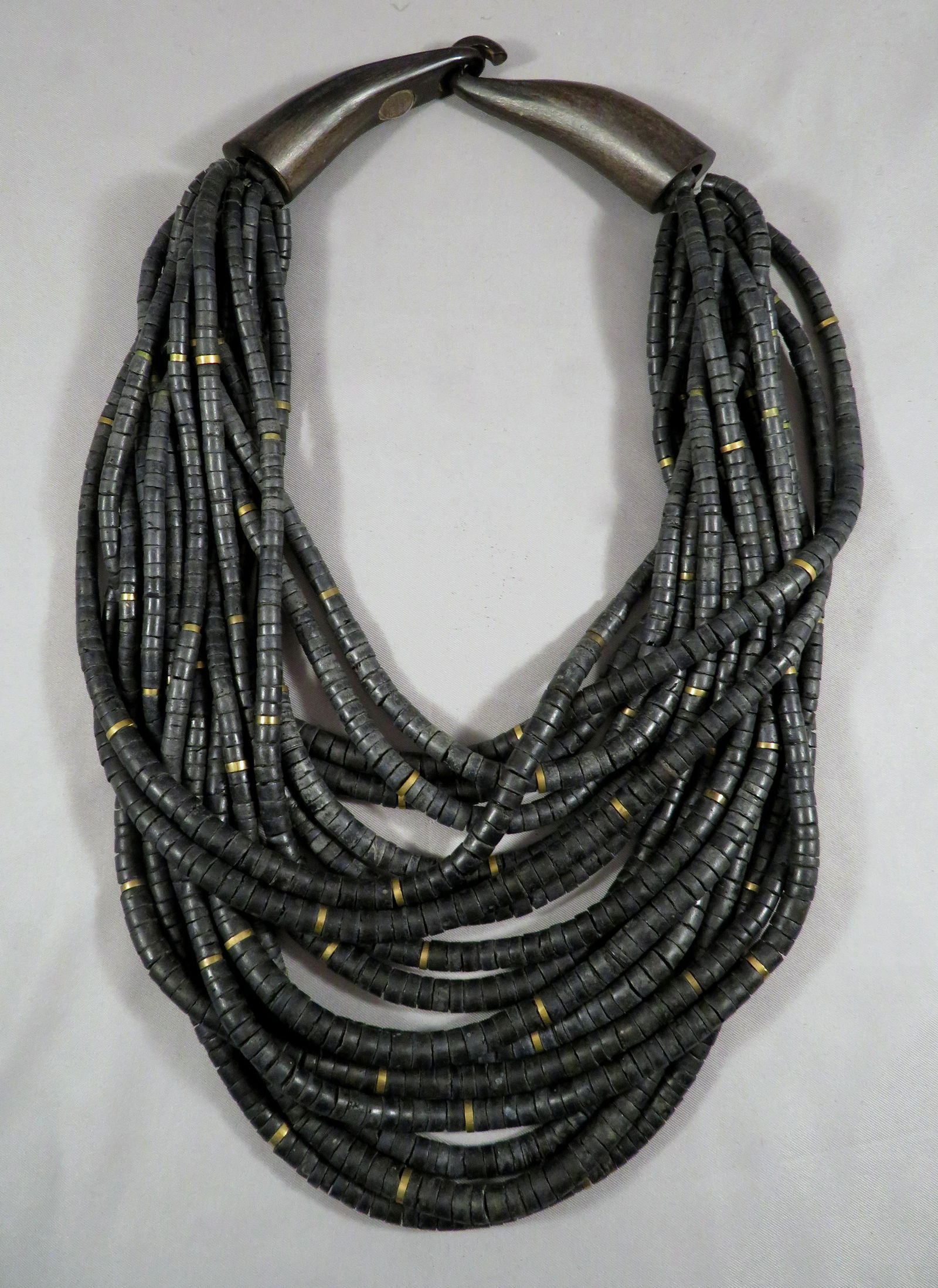 Signed Gerda Lynggaard for Monies Copenhagen Necklace: Designer: Gerda Lynggaard for Monies Materials: Coconut Shell, Wood and Brass Necklace Type: Torsade Period of Manufacture: 1978-1982 Length of Shortest Strand (at neck): 19"(l) Drop Measurement: 12"